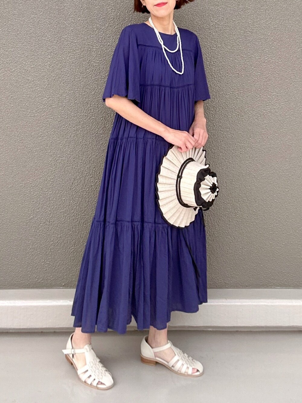 ホワイト系のサンダル、ブルー系のワンピース、ホワイト系のネックレスを着用したレディースの夏コーディネートの2枚目の写真