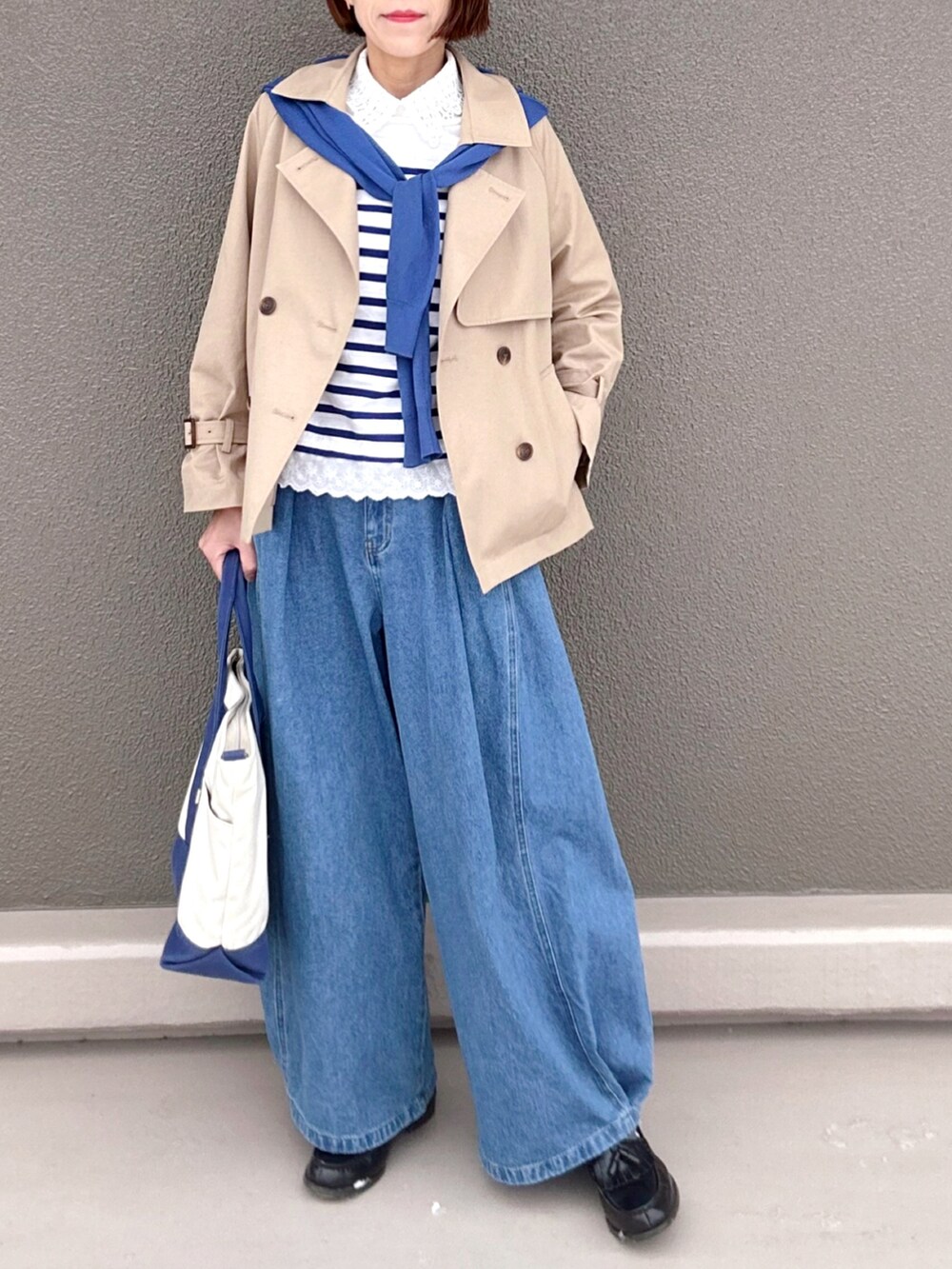 ベージュ系のトレンチコート、ブルー系のデニムパンツ、ホワイト系のTシャツ/カットソーを着用したレディースの春コーディネートの2枚目の写真