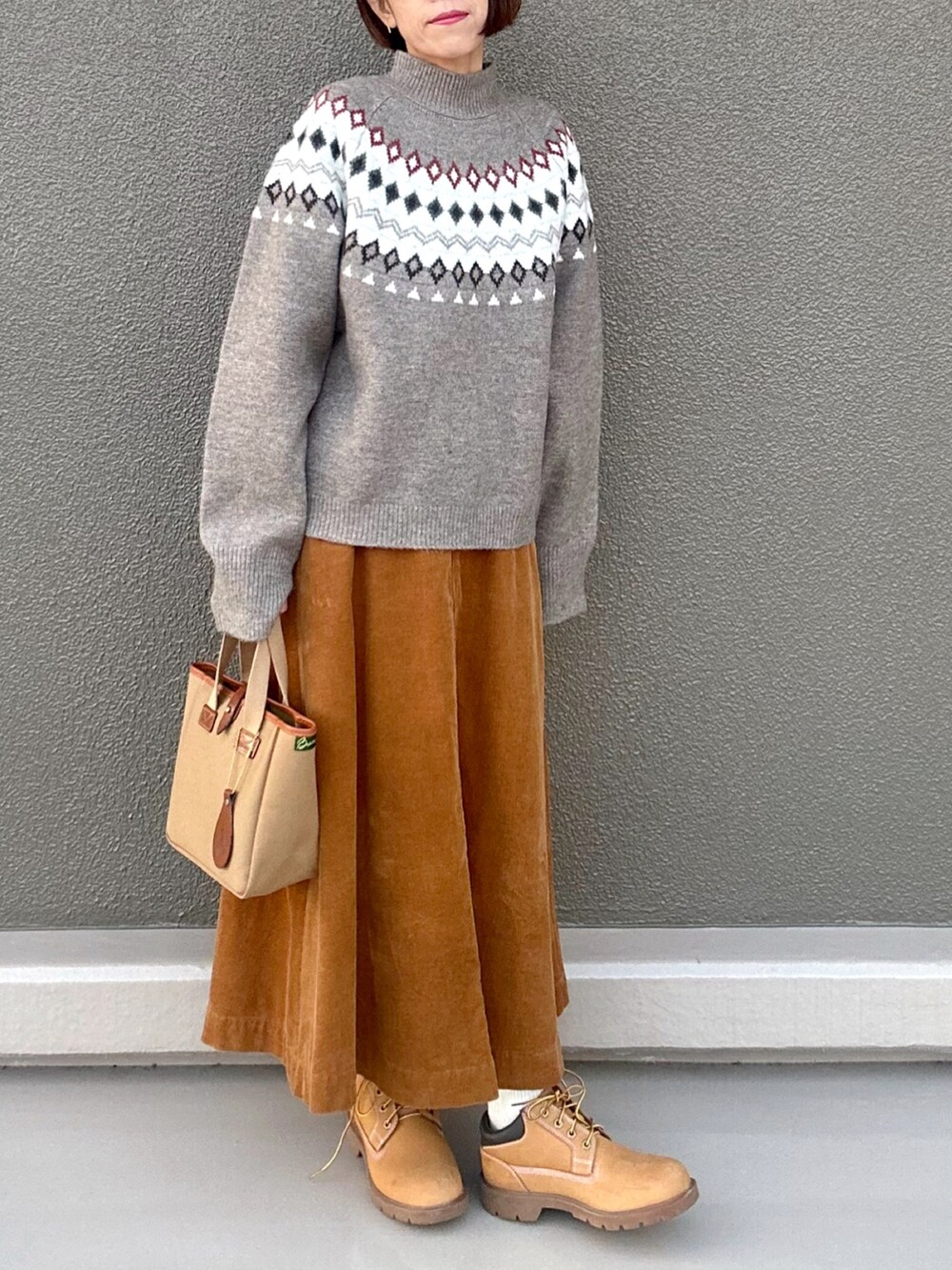 ベージュ系のニット/セーター、イエロー系のスカート、グリーン系のトートバッグを着用したレディースの冬コーディネートの2枚目の写真