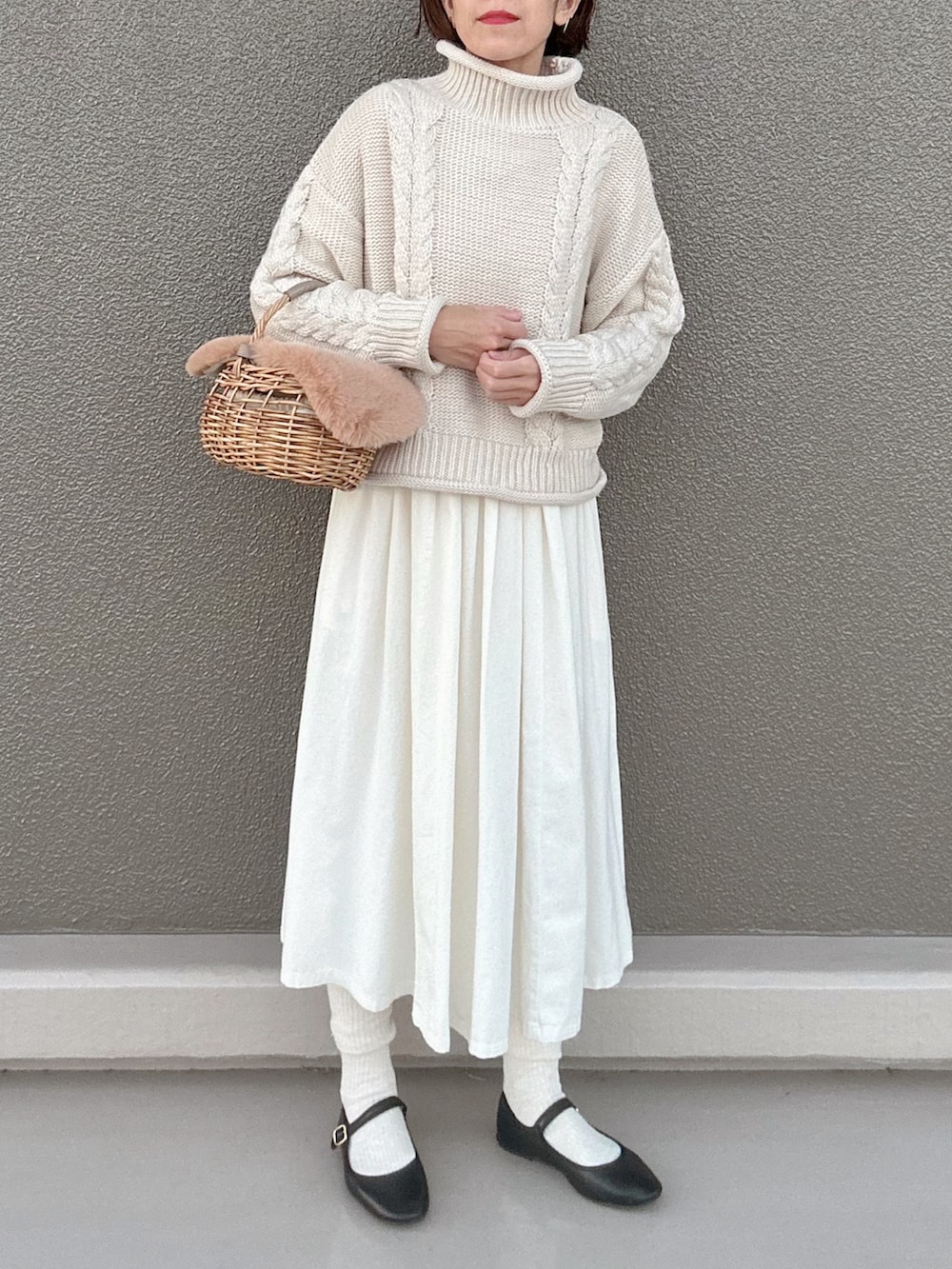 ブラック系のバレエシューズ、ベージュ系のかごバッグ、ホワイト系のワンピースを着用したレディースの冬コーディネートの2枚目の写真