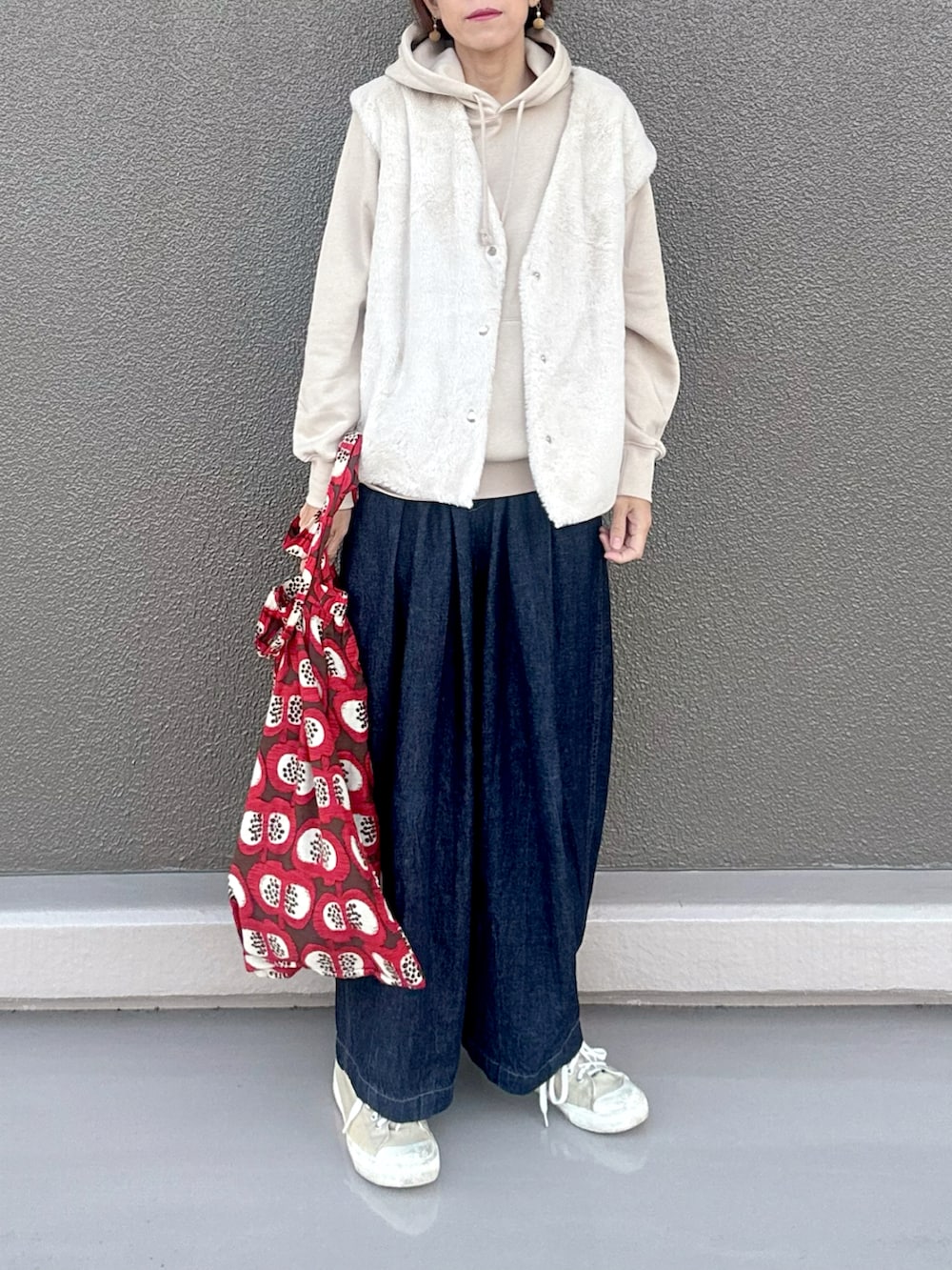 ホワイト系のパーカー、ホワイト系のベスト、ブルー系のデニムパンツを着用したレディースの冬コーディネートの2枚目の写真