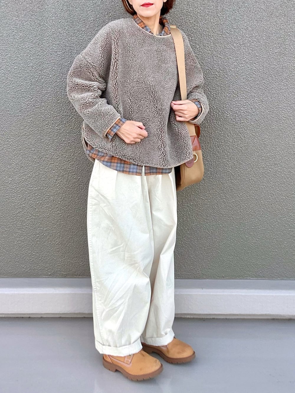 オレンジ系のシャツ/ブラウス、イエロー系のショルダーバッグ、ベージュ系のトップスを着用したレディースの冬コーディネートの2枚目の写真