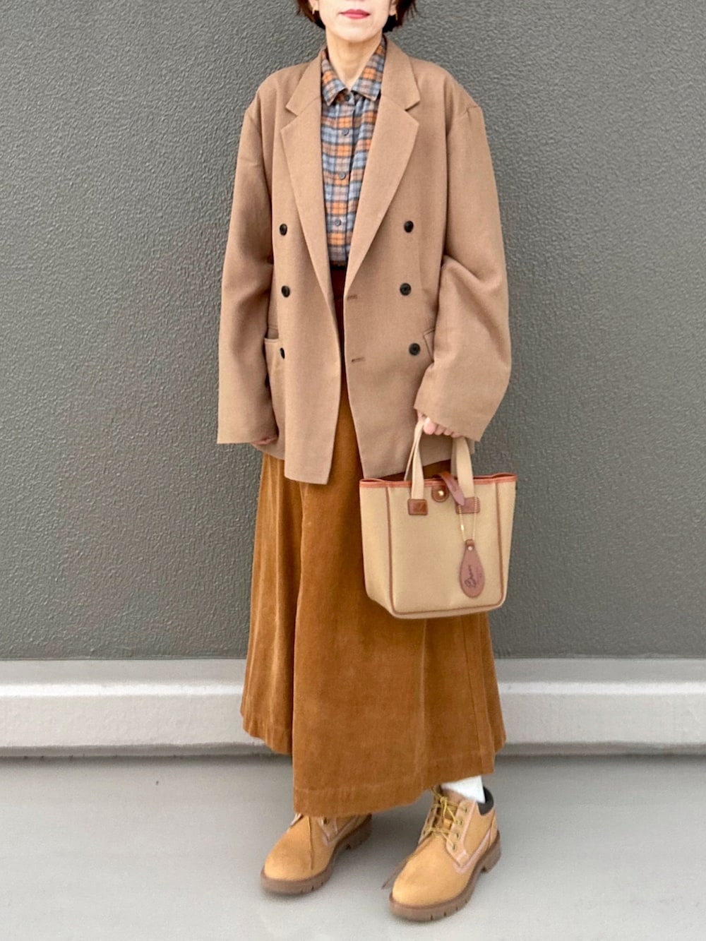 オレンジ系のシャツ/ブラウス、ブラウン系のテーラードジャケット、イエロー系のスカートを着用したレディースの冬コーディネートの2枚目の写真