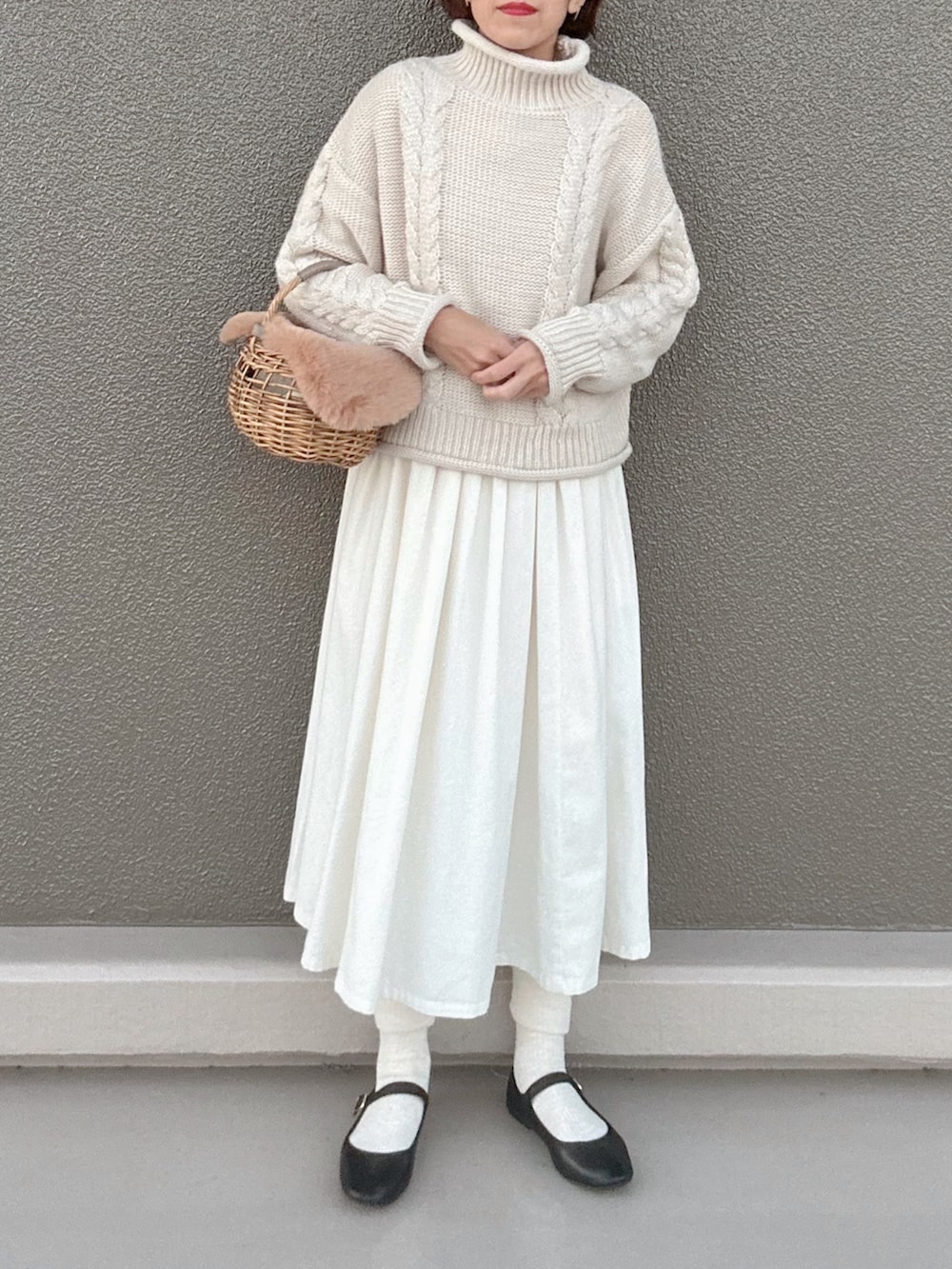 ブラック系のバレエシューズ、ベージュ系のかごバッグ、ホワイト系のワンピースを着用したレディースの冬コーディネートの3枚目の写真