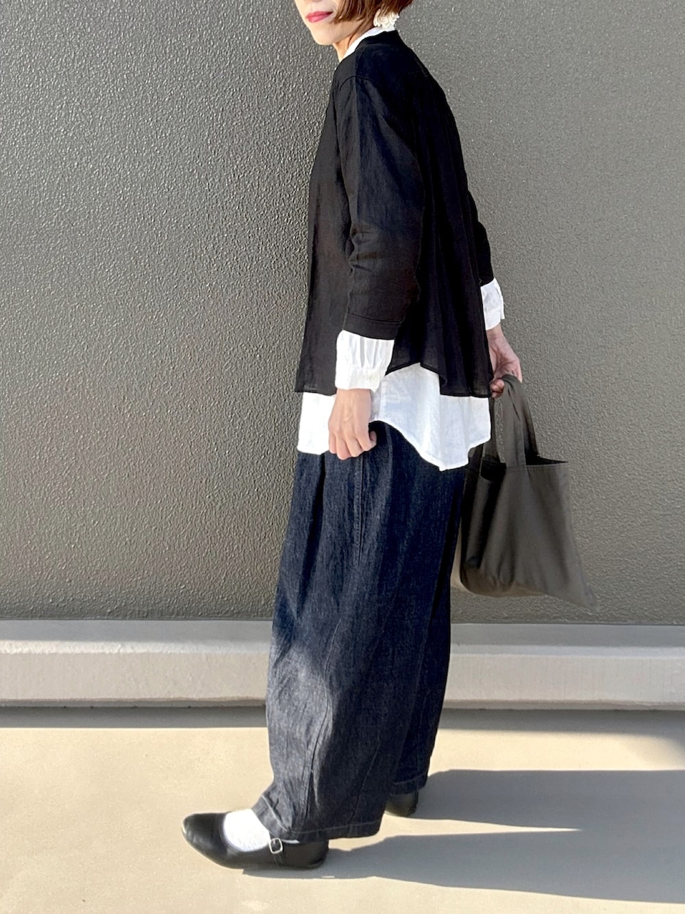 ブラック系のシャツ/ブラウス、ブルー系のデニムパンツ、グレー系のトートバッグを着用したレディースの春コーディネートの2枚目の写真