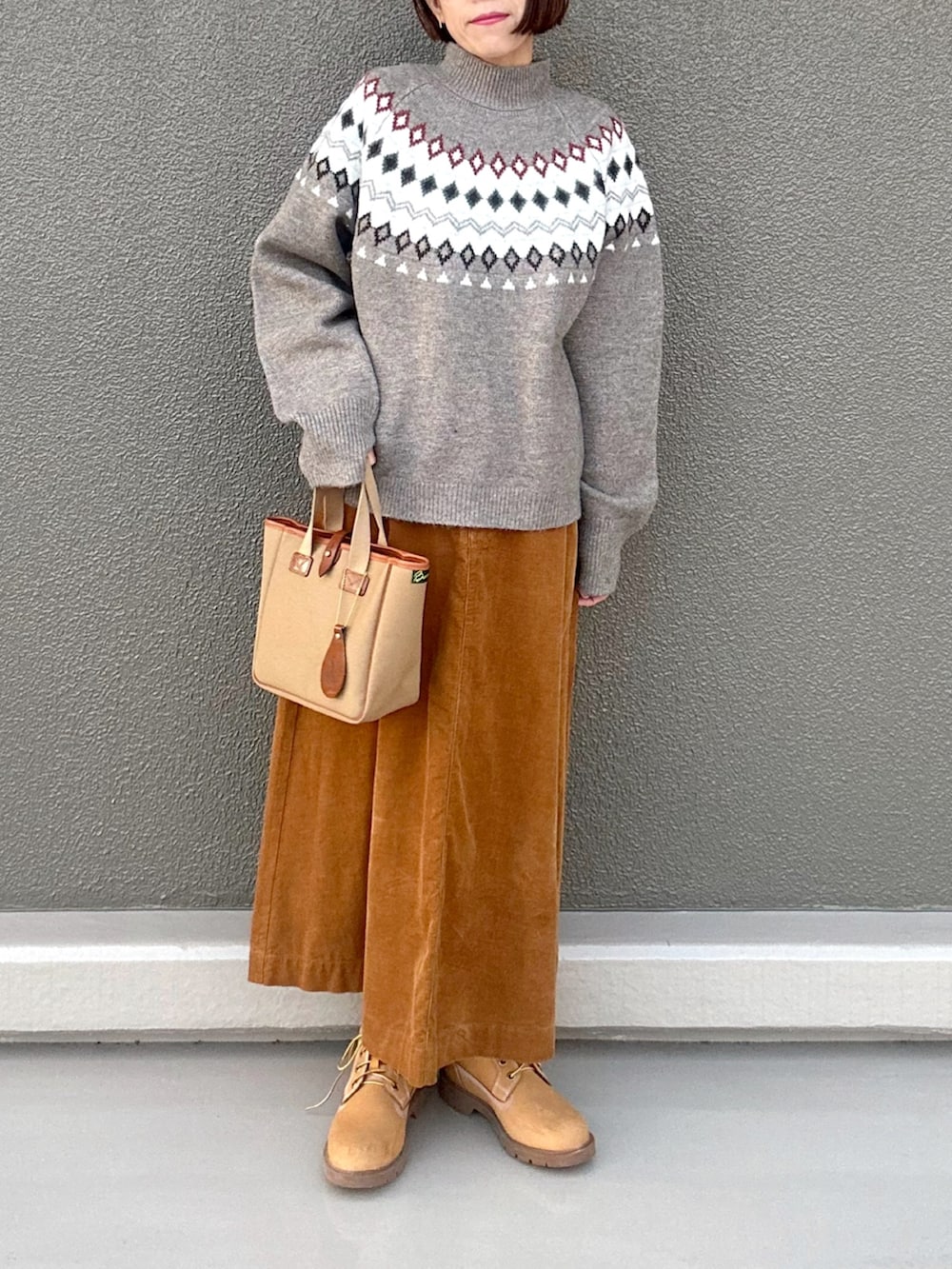 ベージュ系のニット/セーター、イエロー系のスカート、グリーン系のトートバッグを着用したレディースの冬コーディネートの3枚目の写真