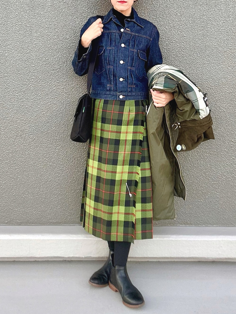 ブラック系のブーツ、ブラック系のニット/セーター、グリーン系のその他アウターを着用したレディースの冬コーディネートの2枚目の写真