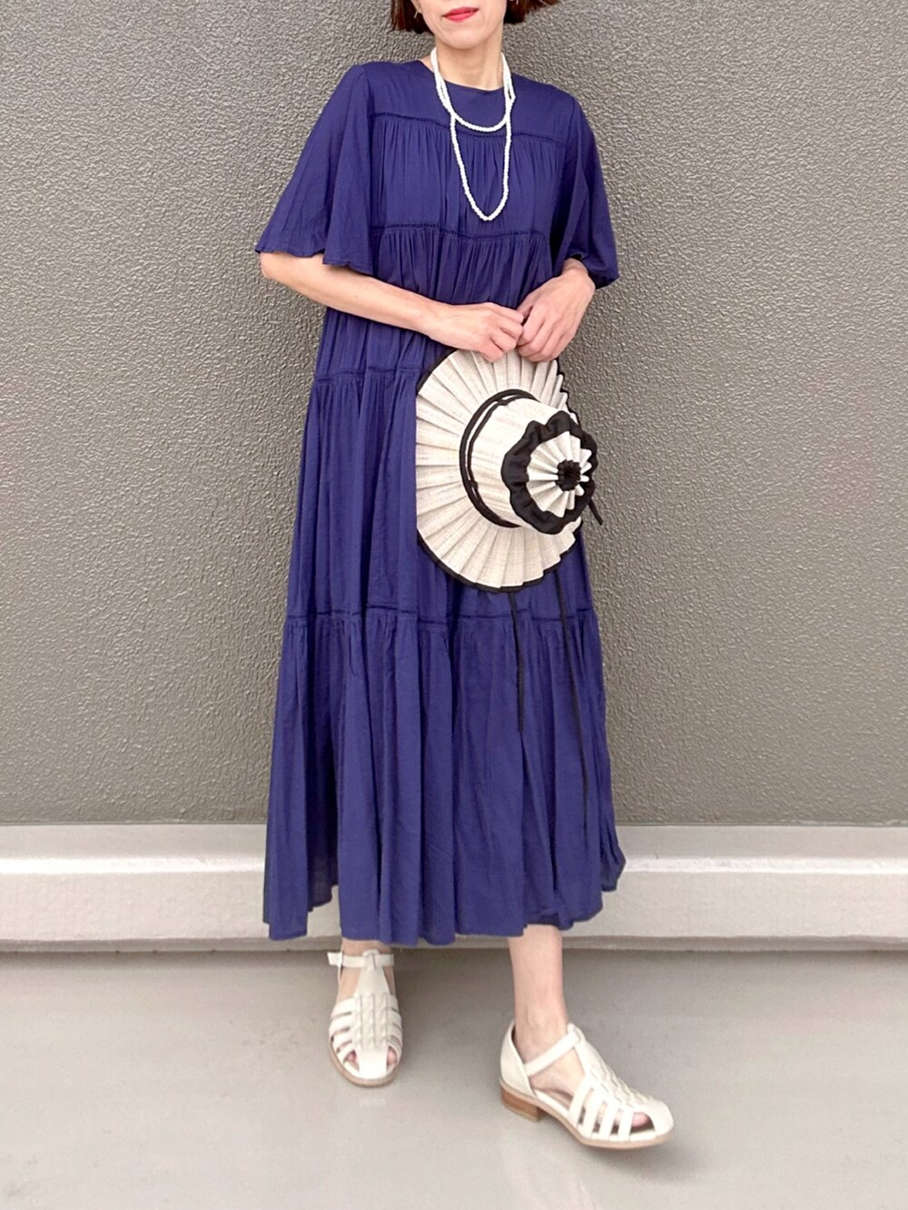 ホワイト系のサンダル、ブルー系のワンピース、ホワイト系のネックレスを着用したレディースの夏コーディネートの3枚目の写真