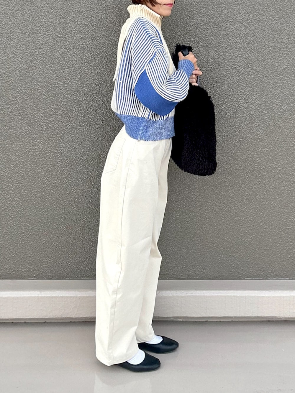 ホワイト系のニット/セーター、ホワイト系のチノパンツ、ブラック系のハンドバッグを着用したレディースの秋コーディネートの2枚目の写真