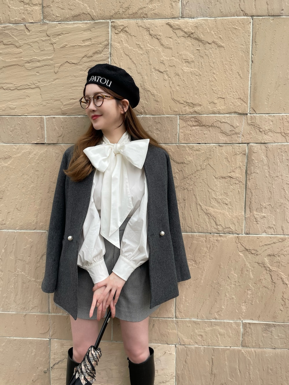 グレー系のノーカラーコート、グレー系のパンツ、ブラック系のハンチング/ベレー帽を着用したレディースの秋コーディネートの2枚目の写真