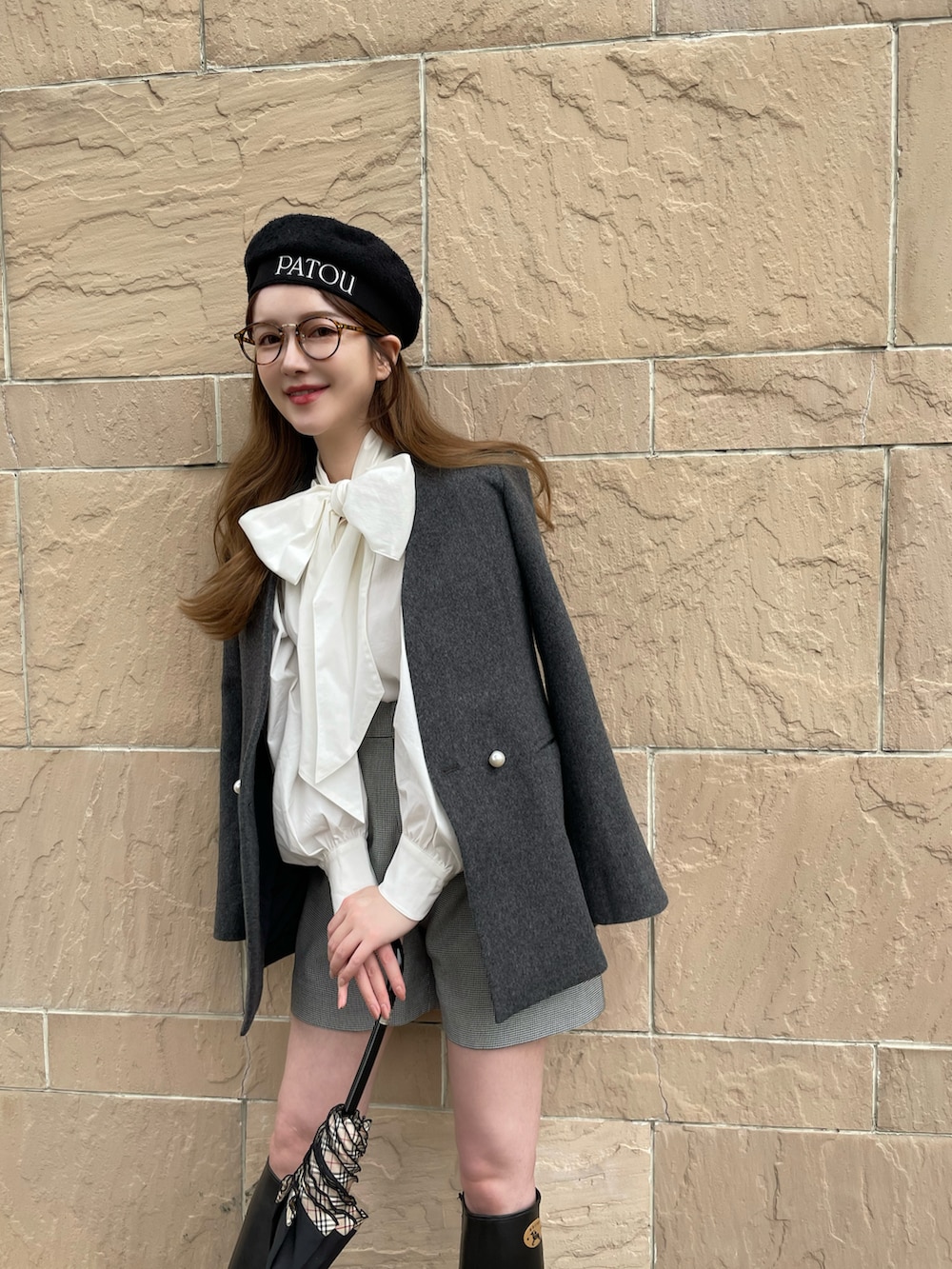 グレー系のノーカラーコート、グレー系のパンツ、ブラック系のハンチング/ベレー帽を着用したレディースの秋コーディネートの3枚目の写真