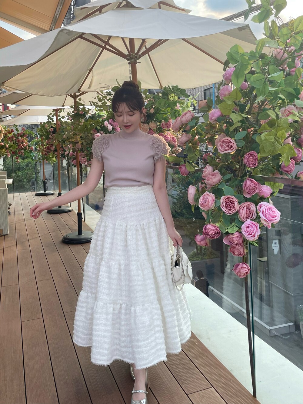 ピンク系のニット/セーター、ホワイト系のスカートを着用したレディースの秋コーディネートの4枚目の写真