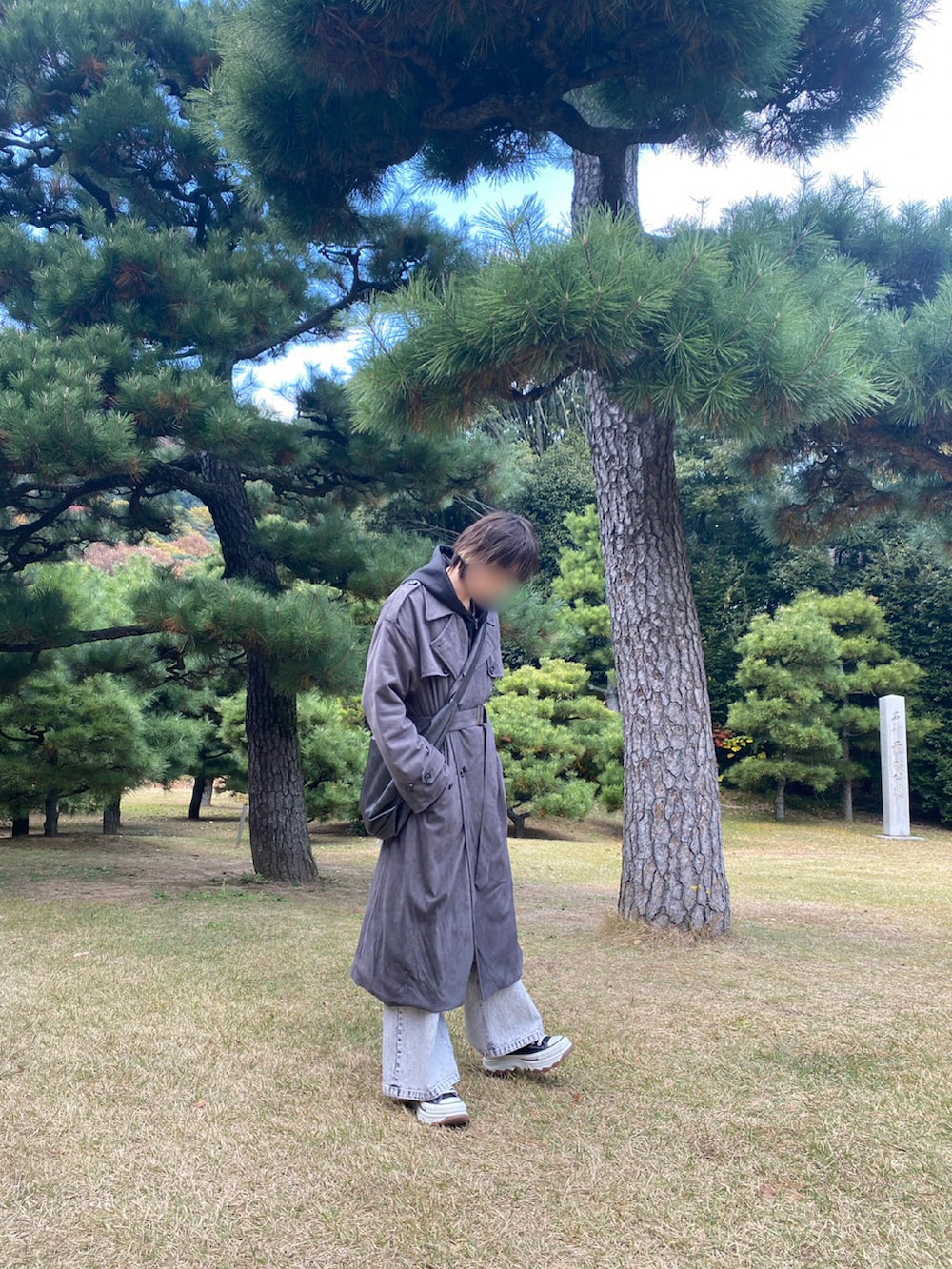 グレー系のトレンチコート、ブラック系のパーカー、ホワイト系のデニムパンツを着用したメンズの冬コーディネートの2枚目の写真