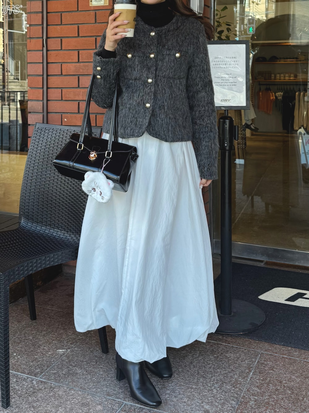 ホワイト系のスカート、グレー系のジャケット/アウター、ブラック系のブーツを着用したレディースの冬コーディネートの3枚目の写真