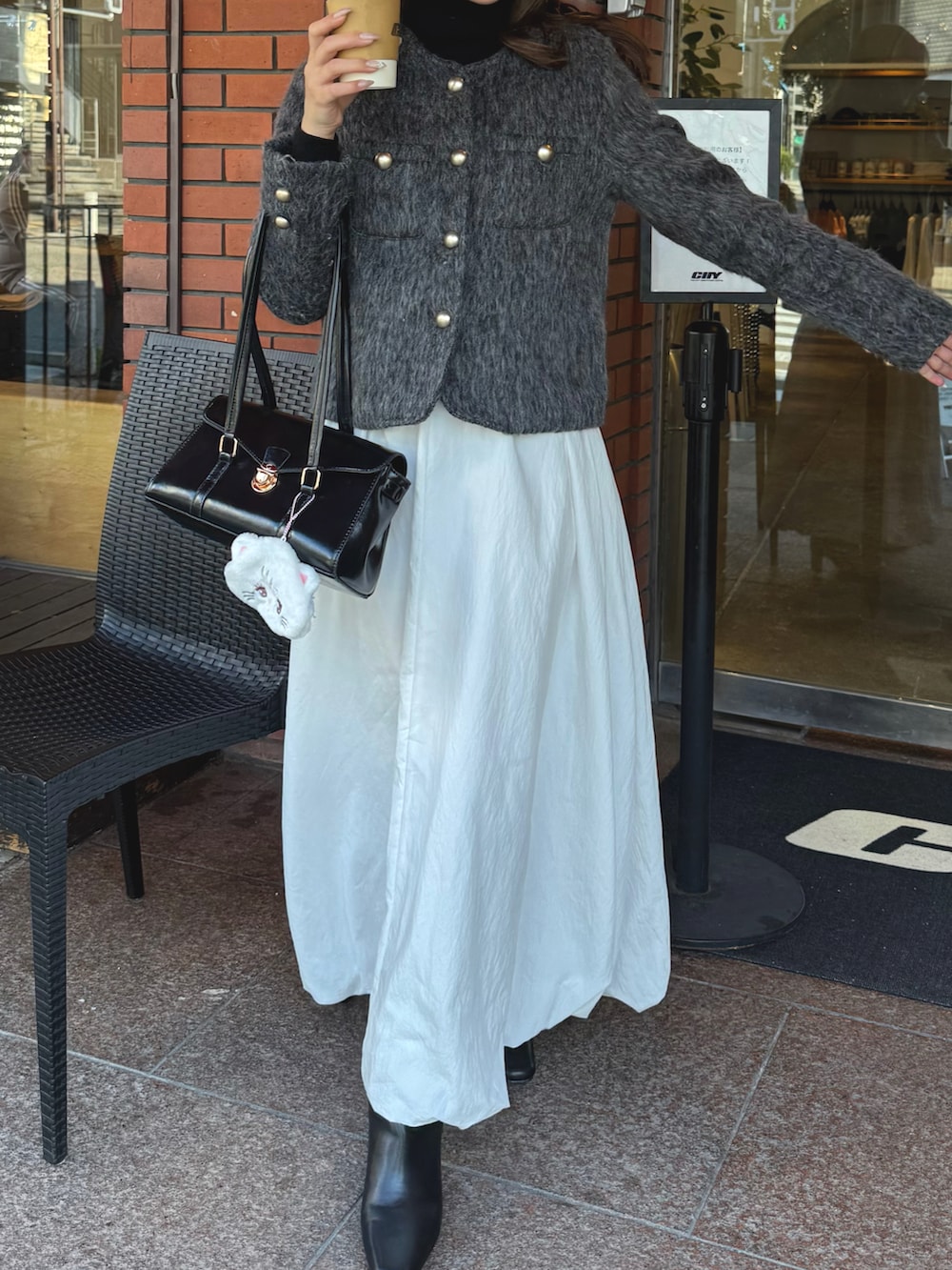 ホワイト系のスカート、グレー系のジャケット/アウター、ブラック系のブーツを着用したレディースの冬コーディネートの5枚目の写真
