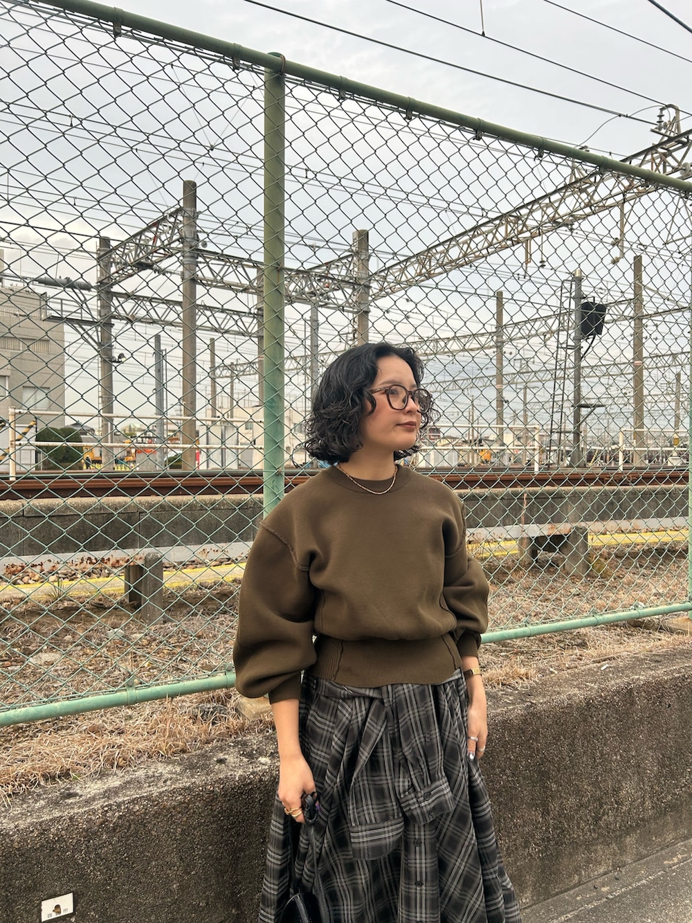 グリーン系のニット/セーター、ブラック系のスカート、ブラック系のブーツを着用したレディースの冬コーディネートの3枚目の写真