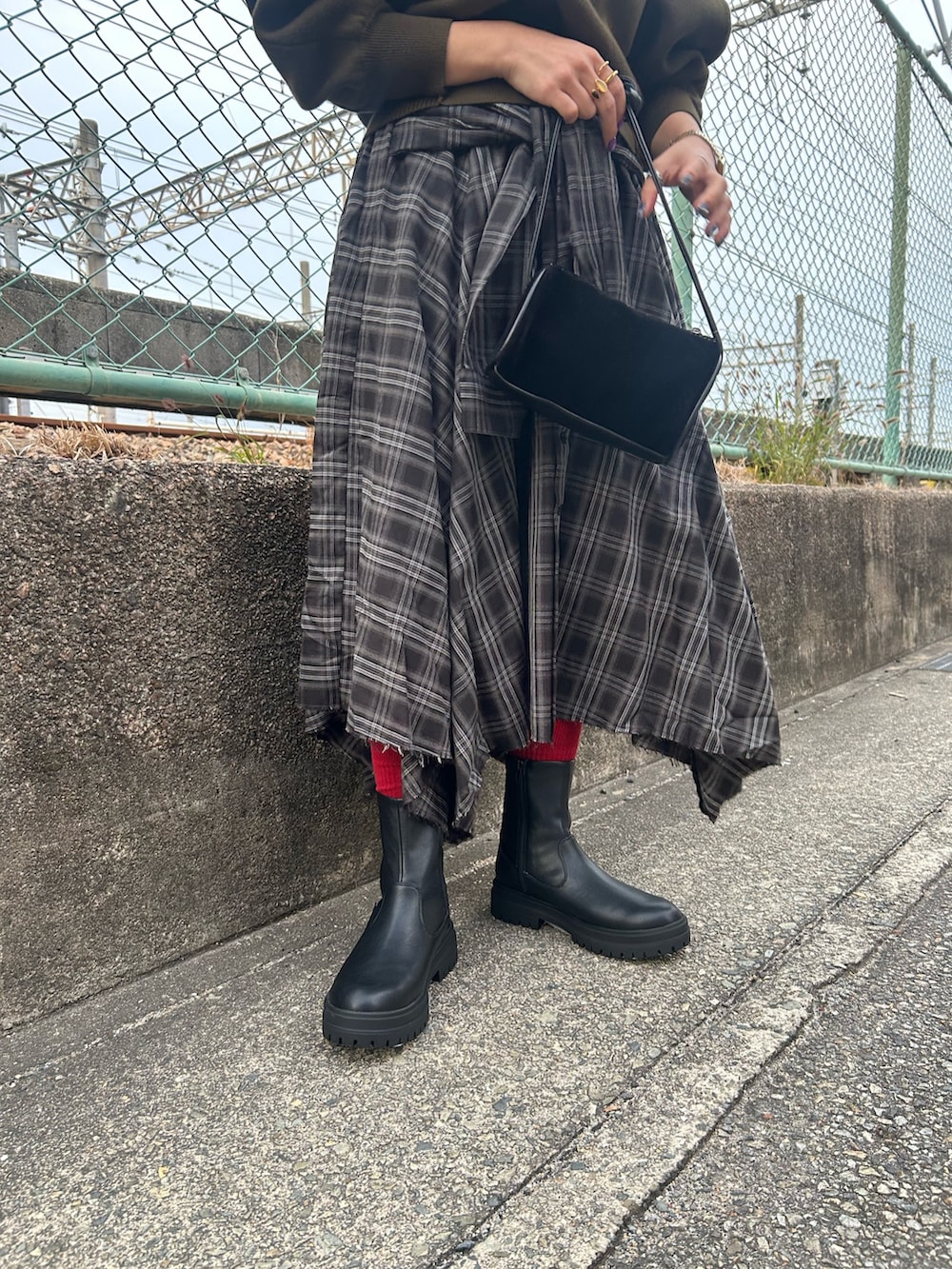 グリーン系のニット/セーター、ブラック系のスカート、ブラック系のブーツを着用したレディースの冬コーディネートの5枚目の写真