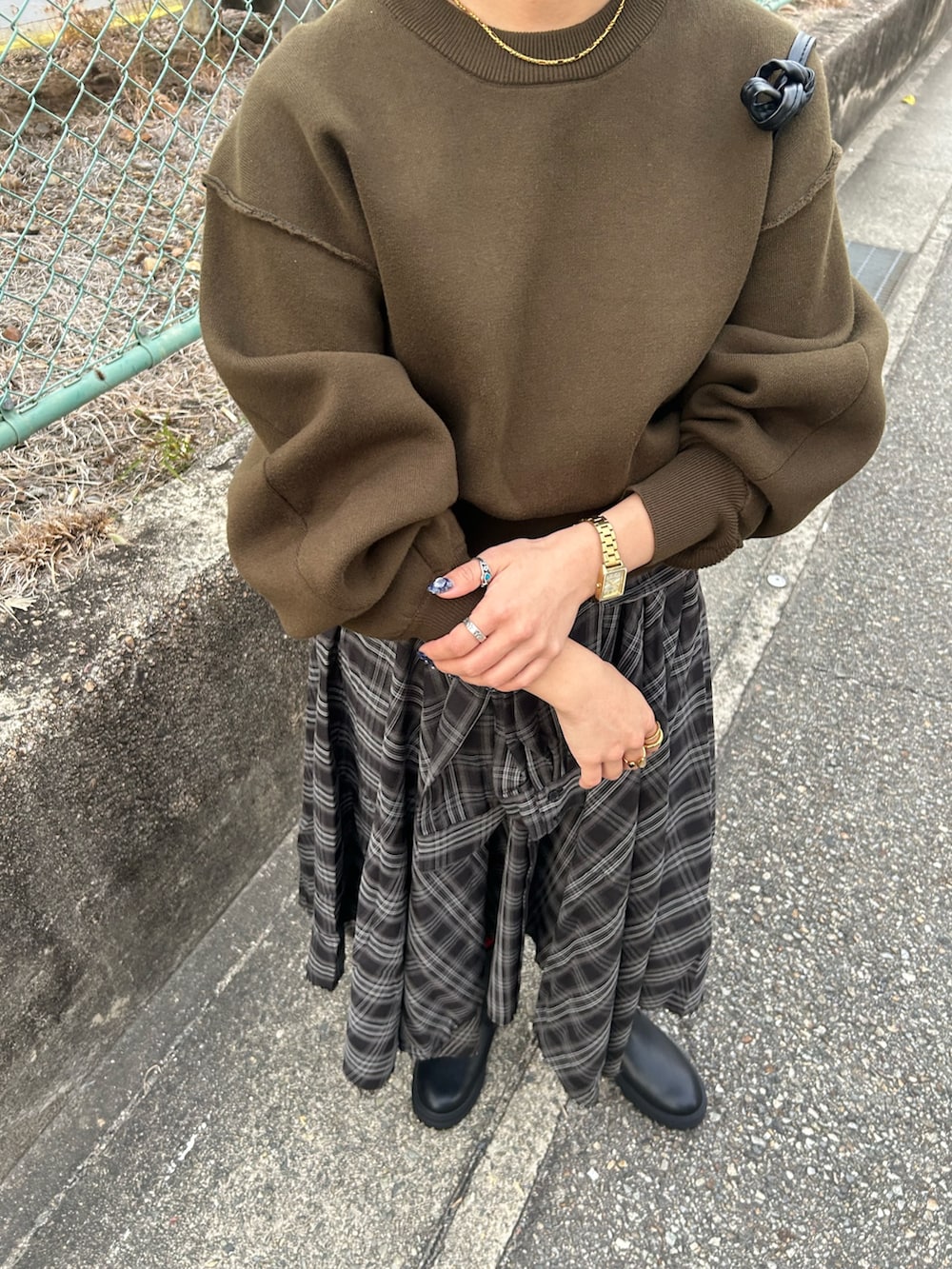 グリーン系のニット/セーター、ブラック系のスカート、ブラック系のブーツを着用したレディースの冬コーディネートの6枚目の写真