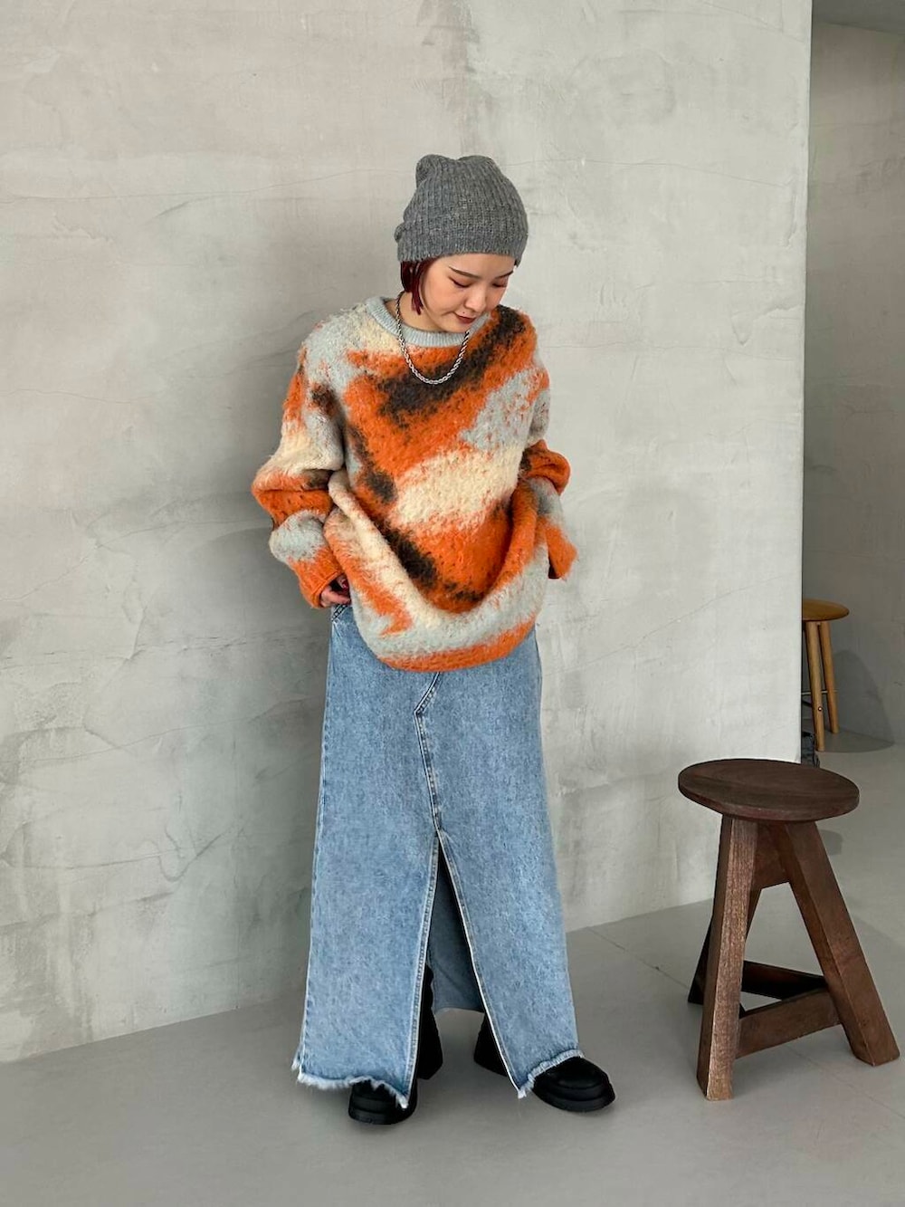 ブラック系のブーツ、オレンジ系のニット/セーター、グレー系のニットキャップ/ビーニーを着用したレディースの秋コーディネートの2枚目の写真
