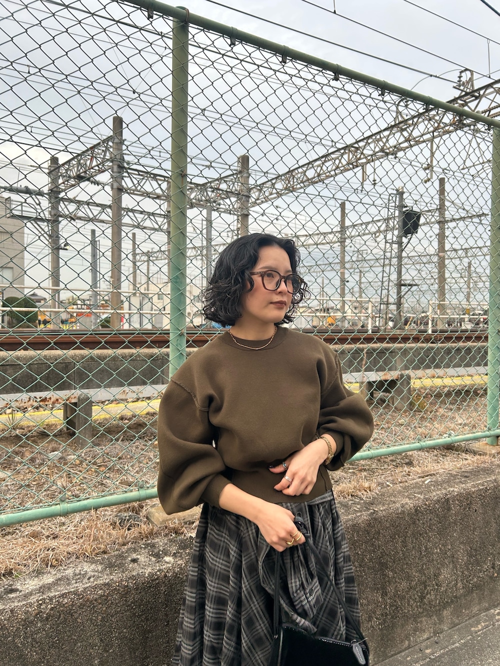 グリーン系のニット/セーター、ブラック系のスカート、ブラック系のブーツを着用したレディースの冬コーディネートの4枚目の写真