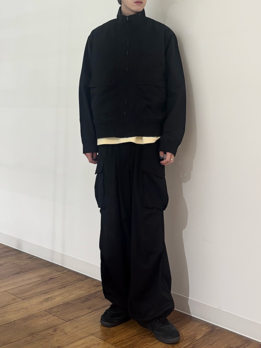 ブラック系のブルゾン、イエロー系のTシャツ/カットソー、ブラック系のカーゴパンツを着用したメンズの春コーディネートの4枚目の写真