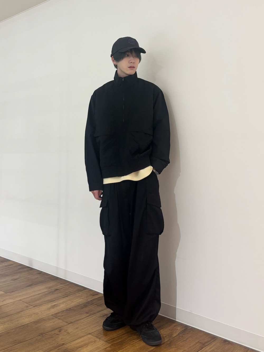 ブラック系のブルゾン、イエロー系のTシャツ/カットソー、ブラック系のカーゴパンツを着用したメンズの春コーディネートの2枚目の写真