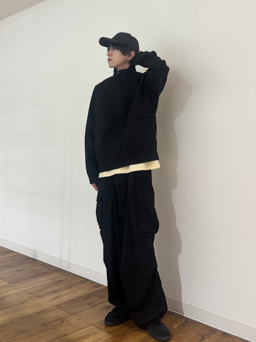 ブラック系のブルゾン、イエロー系のTシャツ/カットソー、ブラック系のカーゴパンツを着用したメンズの春コーディネートの3枚目の写真