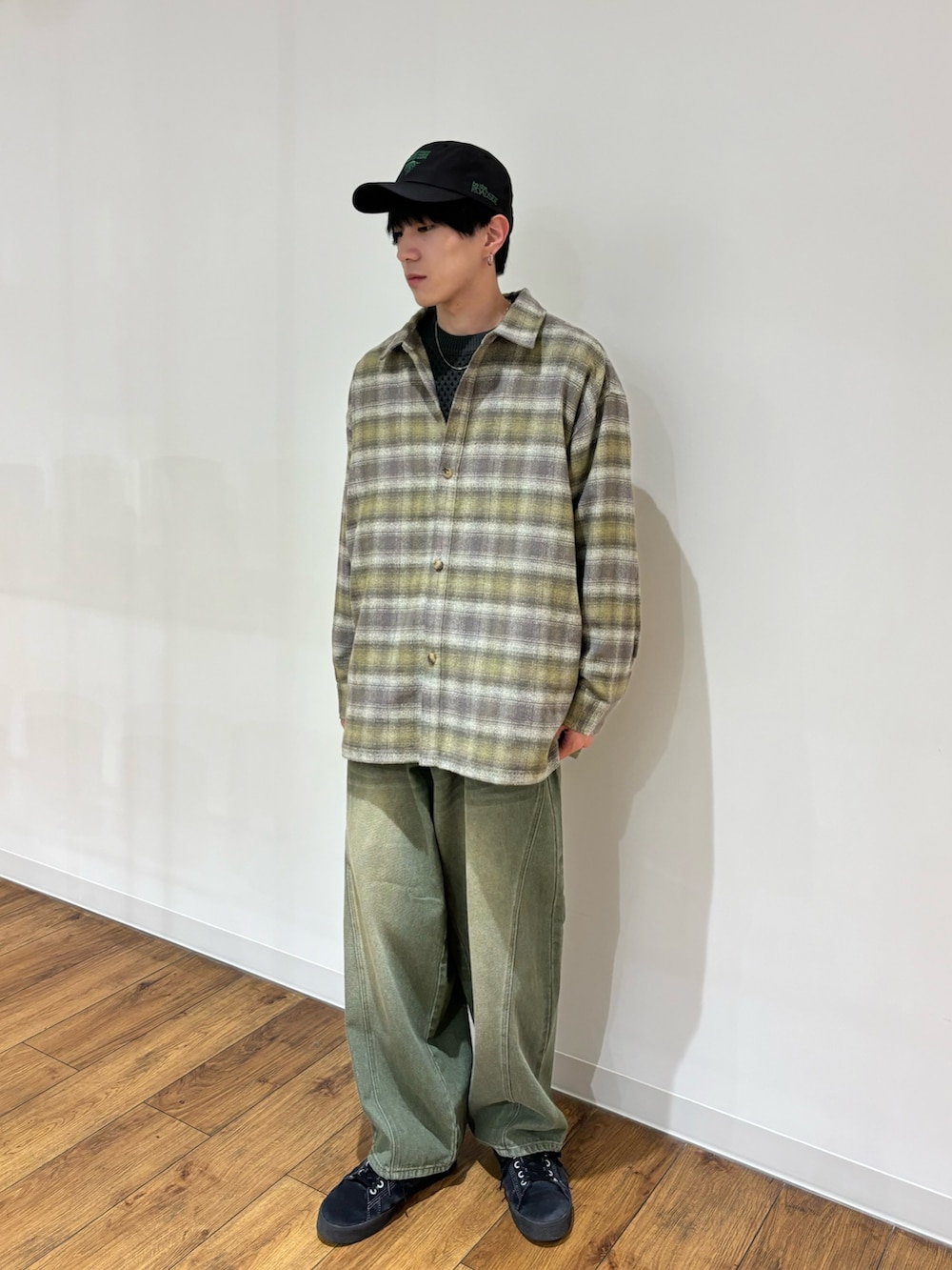 グレー系のニット/セーター、ベージュ系のシャツ/ブラウス、グリーン系のデニムパンツを着用したメンズの秋コーディネートの2枚目の写真