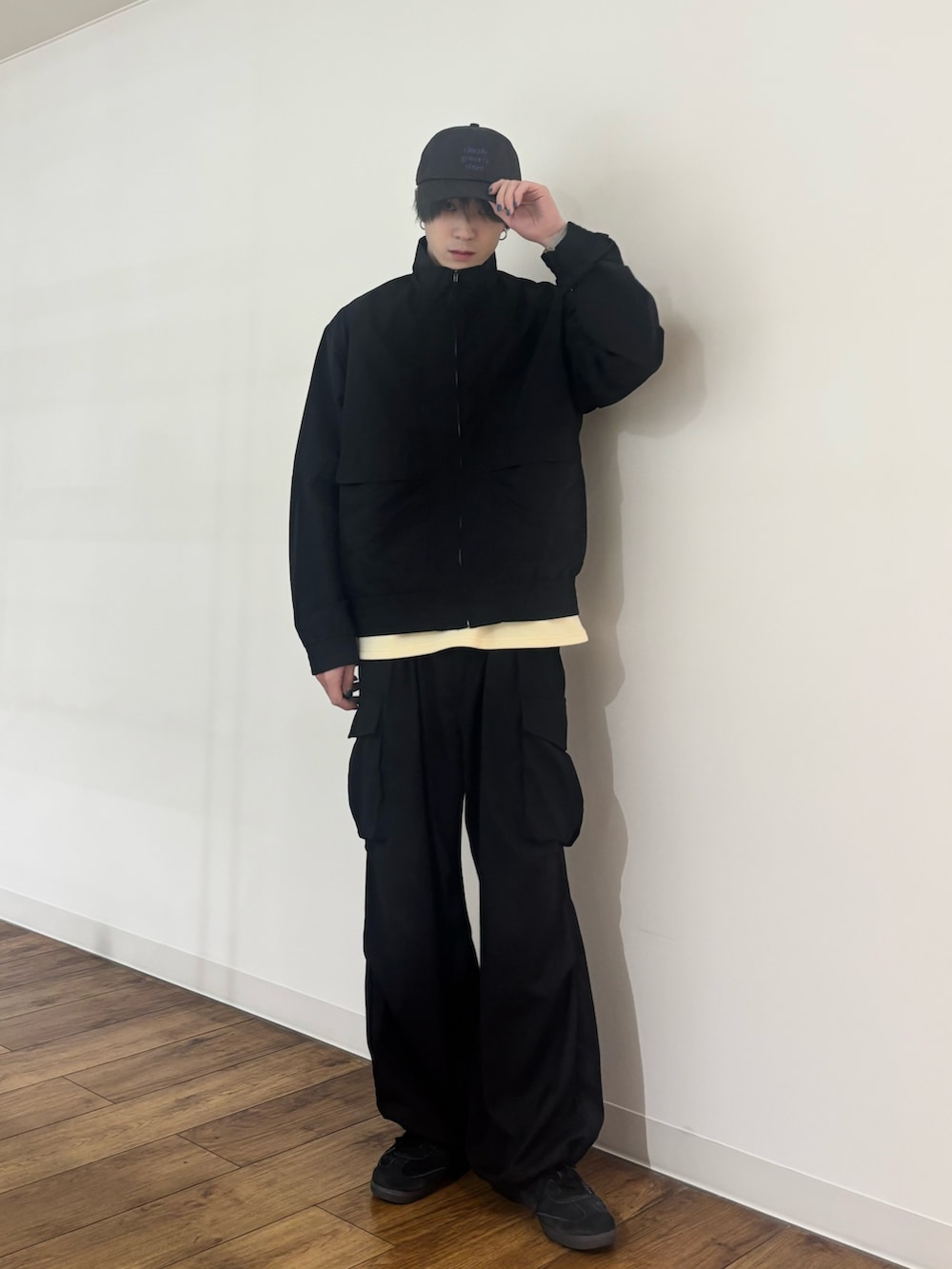 ブラック系のブルゾン、イエロー系のTシャツ/カットソー、ブラック系のカーゴパンツを着用したメンズの春コーディネートの7枚目の写真