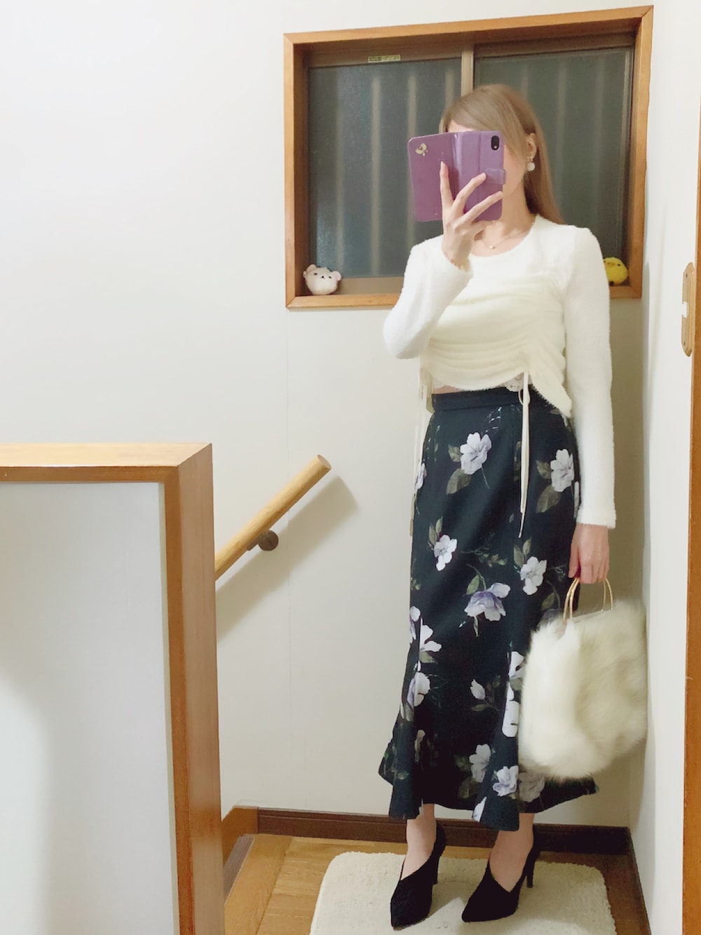 ブラック系のパンプス、ブラック系のスカート、ホワイト系のハンドバッグを着用したレディースの秋コーディネートの2枚目の写真