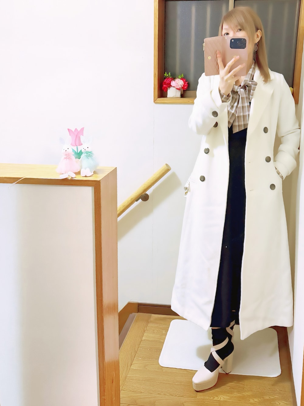 ホワイト系のチェスターコート、ブラック系のジャンパースカート、ホワイト系のショルダーバッグを着用したレディースの冬コーディネートの2枚目の写真