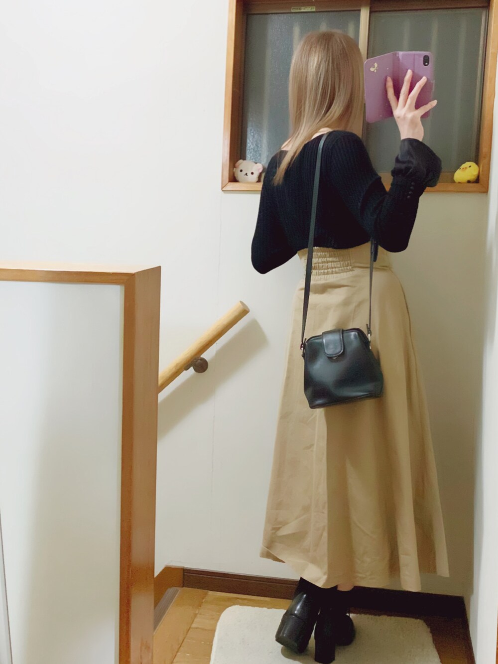 ブラック系のブーツ、ベージュ系のスカート、ブラック系のショルダーバッグを着用したレディースの冬コーディネートの5枚目の写真