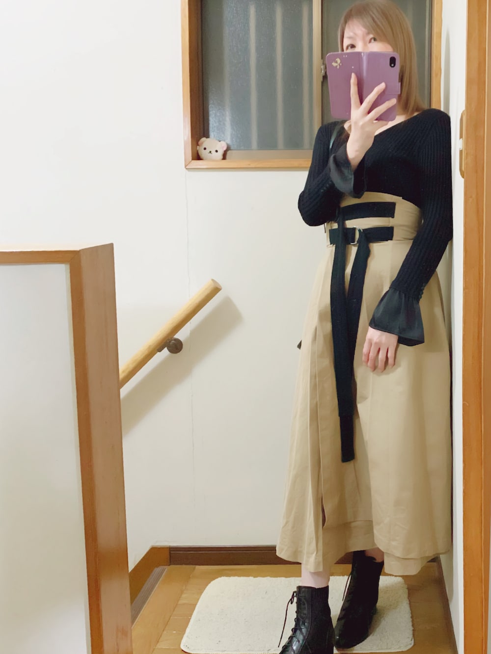 ブラック系のブーツ、ベージュ系のスカート、ブラック系のショルダーバッグを着用したレディースの冬コーディネートの2枚目の写真