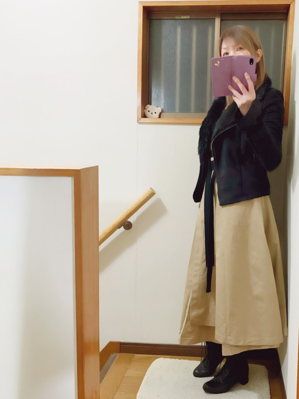 ブラック系のブーツ、ベージュ系のスカート、ブラック系のショルダーバッグを着用したレディースの冬コーディネートの3枚目の写真