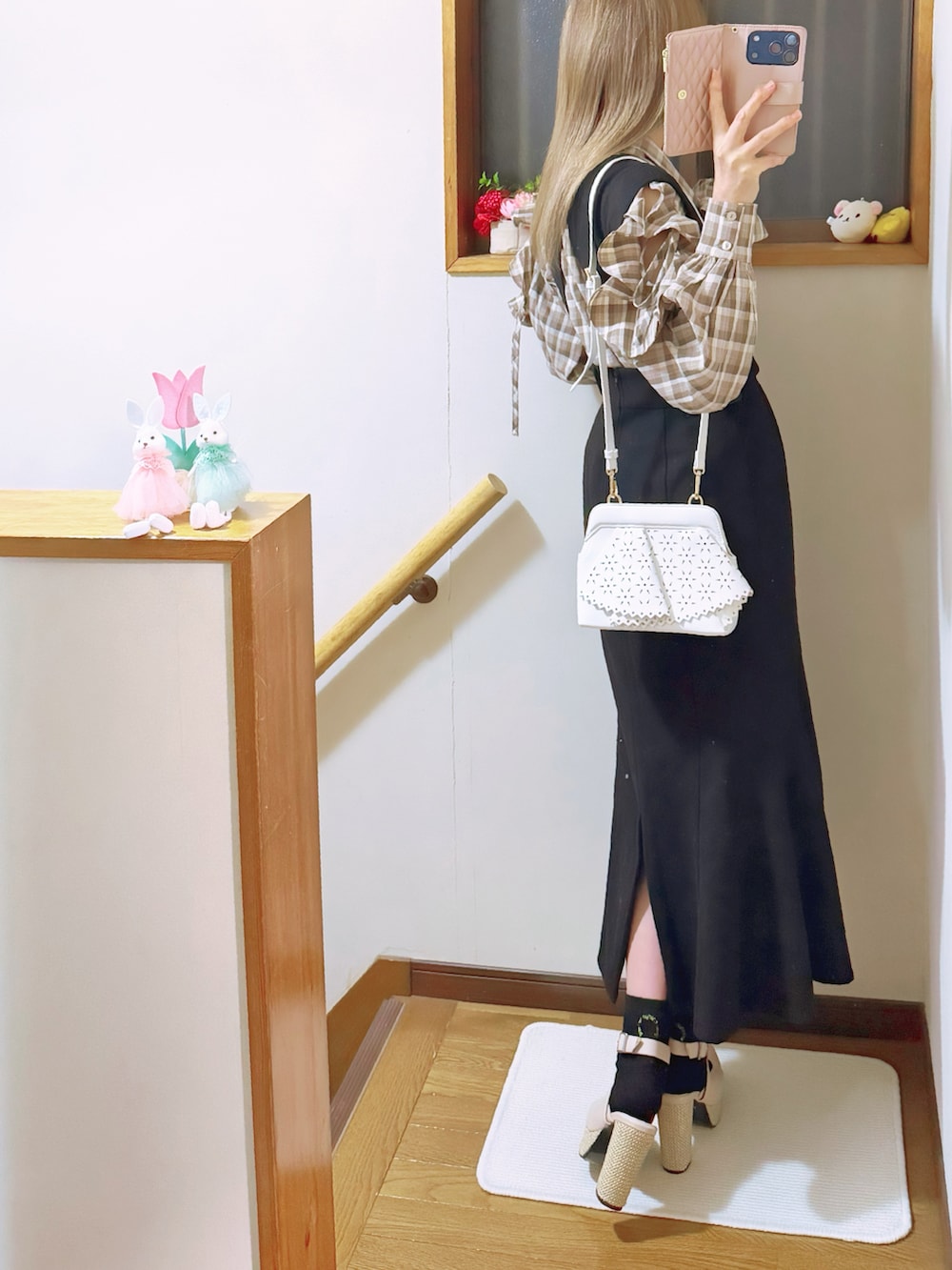 ホワイト系のチェスターコート、ブラック系のジャンパースカート、ホワイト系のショルダーバッグを着用したレディースの冬コーディネートの4枚目の写真