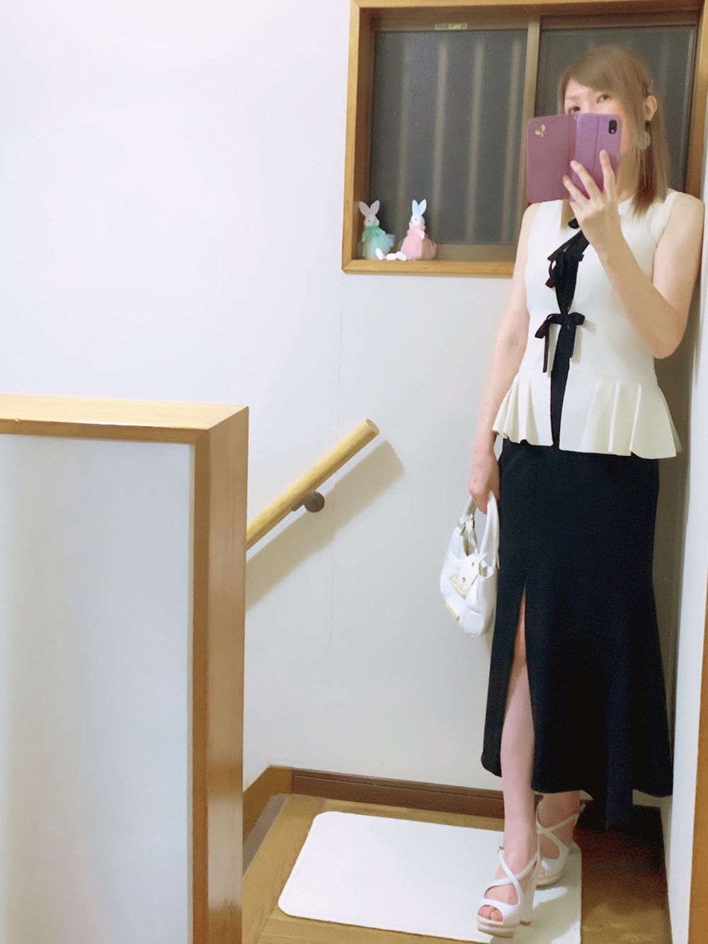 ブラック系のスカート、ホワイト系のショルダーバッグ、ホワイト系のニット/セーターを着用したレディースの夏コーディネートの2枚目の写真