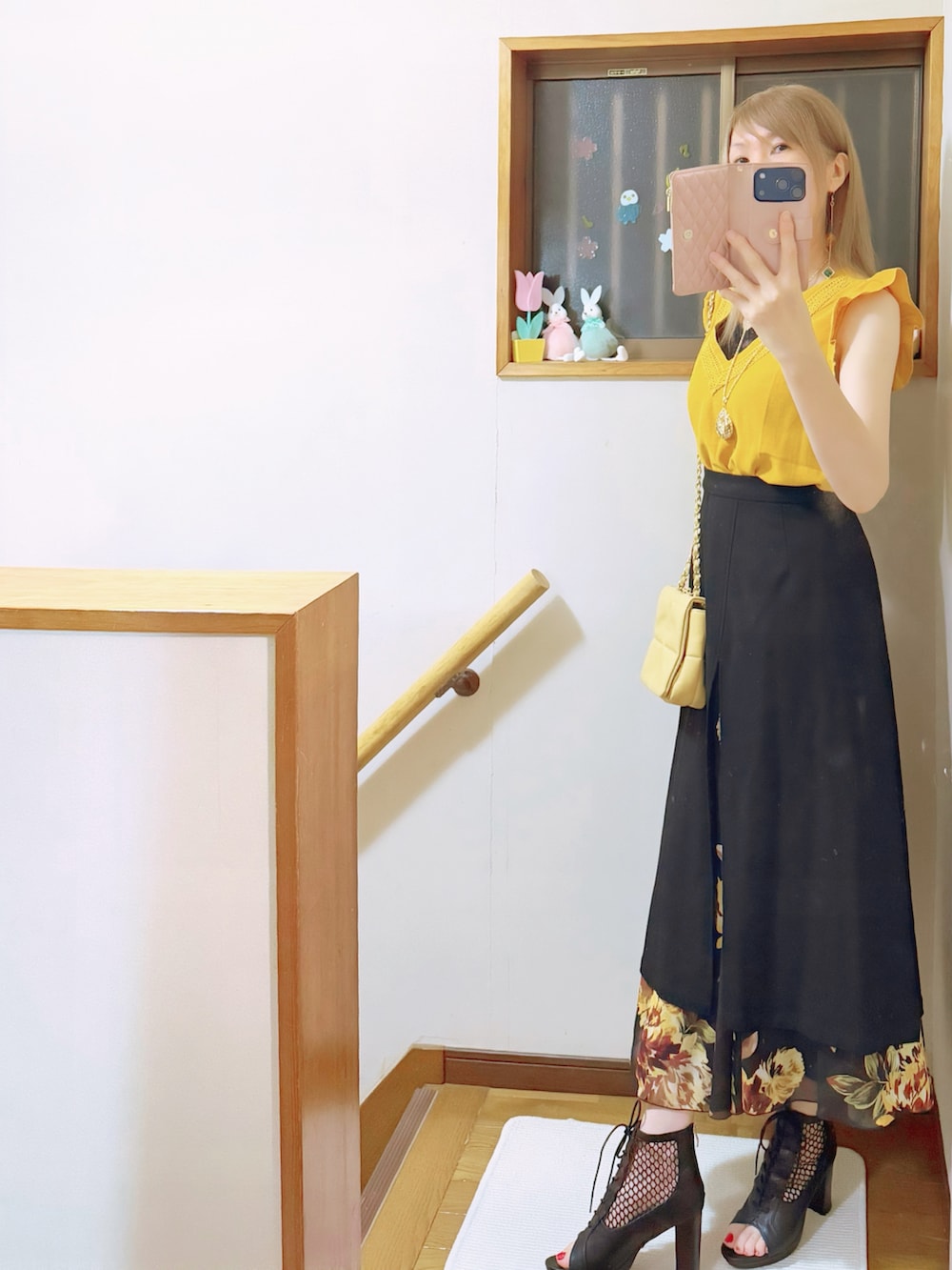 ブラック系のスカート、イエロー系のショルダーバッグ、ブラック系のブーツを着用したレディースの夏コーディネートの2枚目の写真