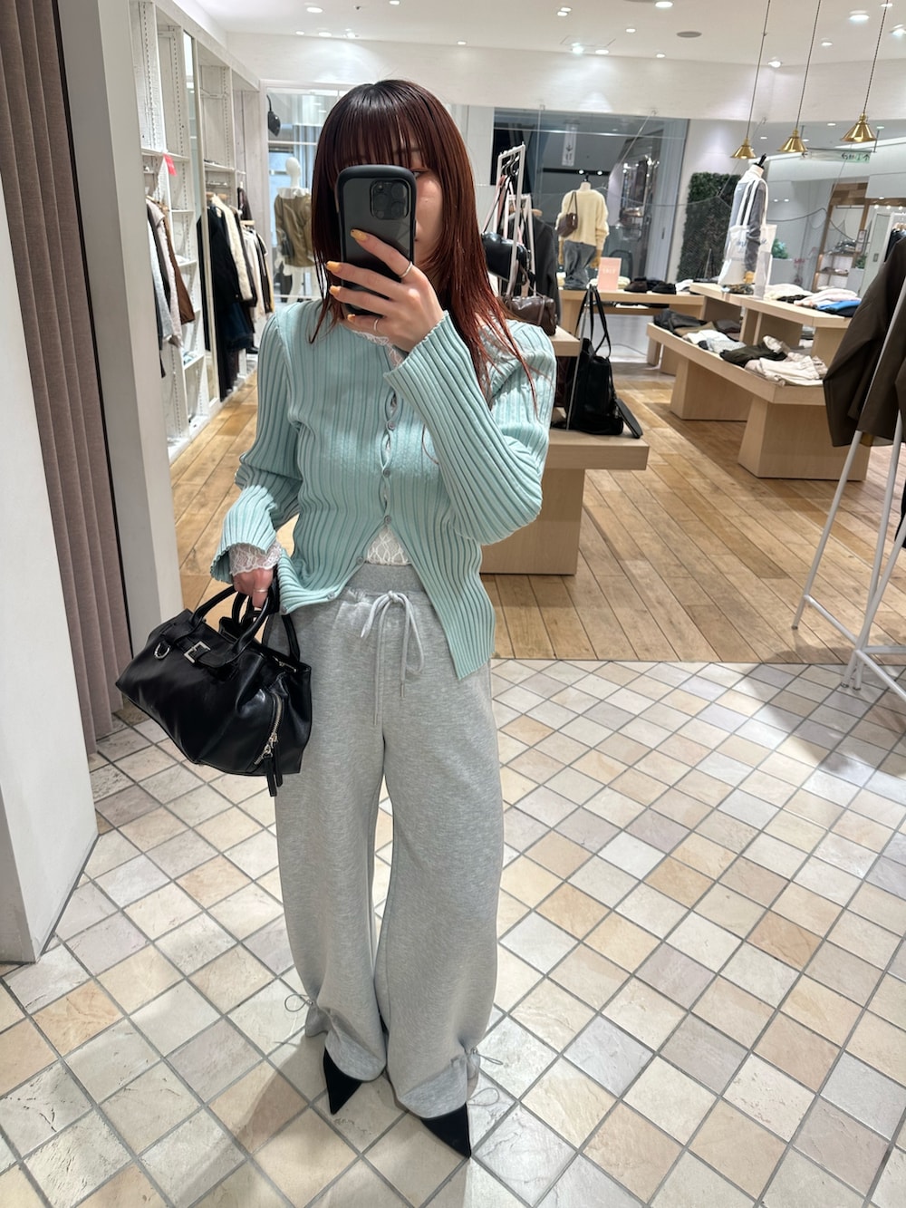 グリーン系のカーディガン/ボレロ、ホワイト系のキャミソール、ホワイト系のTシャツ/カットソーを着用したレディースの冬コーディネートの2枚目の写真