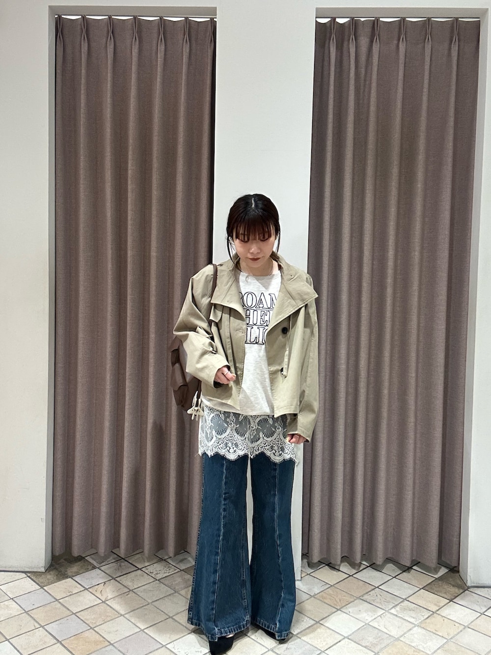 ベージュ系のトレンチコート、グレー系のパーカー、イエロー系のトートバッグを着用したレディースの冬コーディネートの2枚目の写真