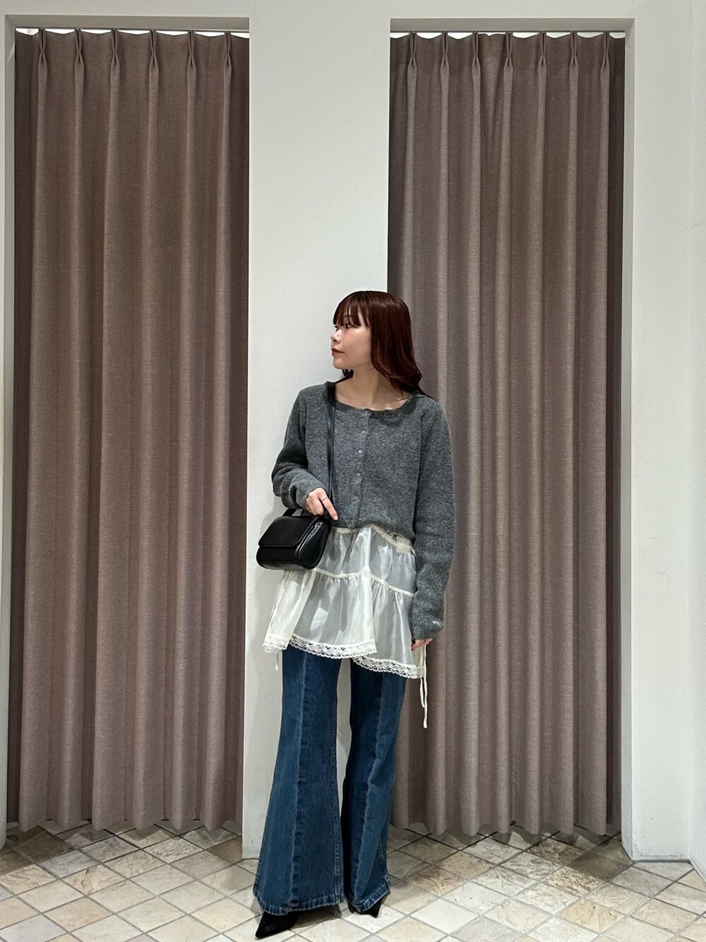 ブラック系のその他アウター、ブラック系のトートバッグ、ブルー系のデニムパンツを着用したレディースの秋コーディネートの5枚目の写真