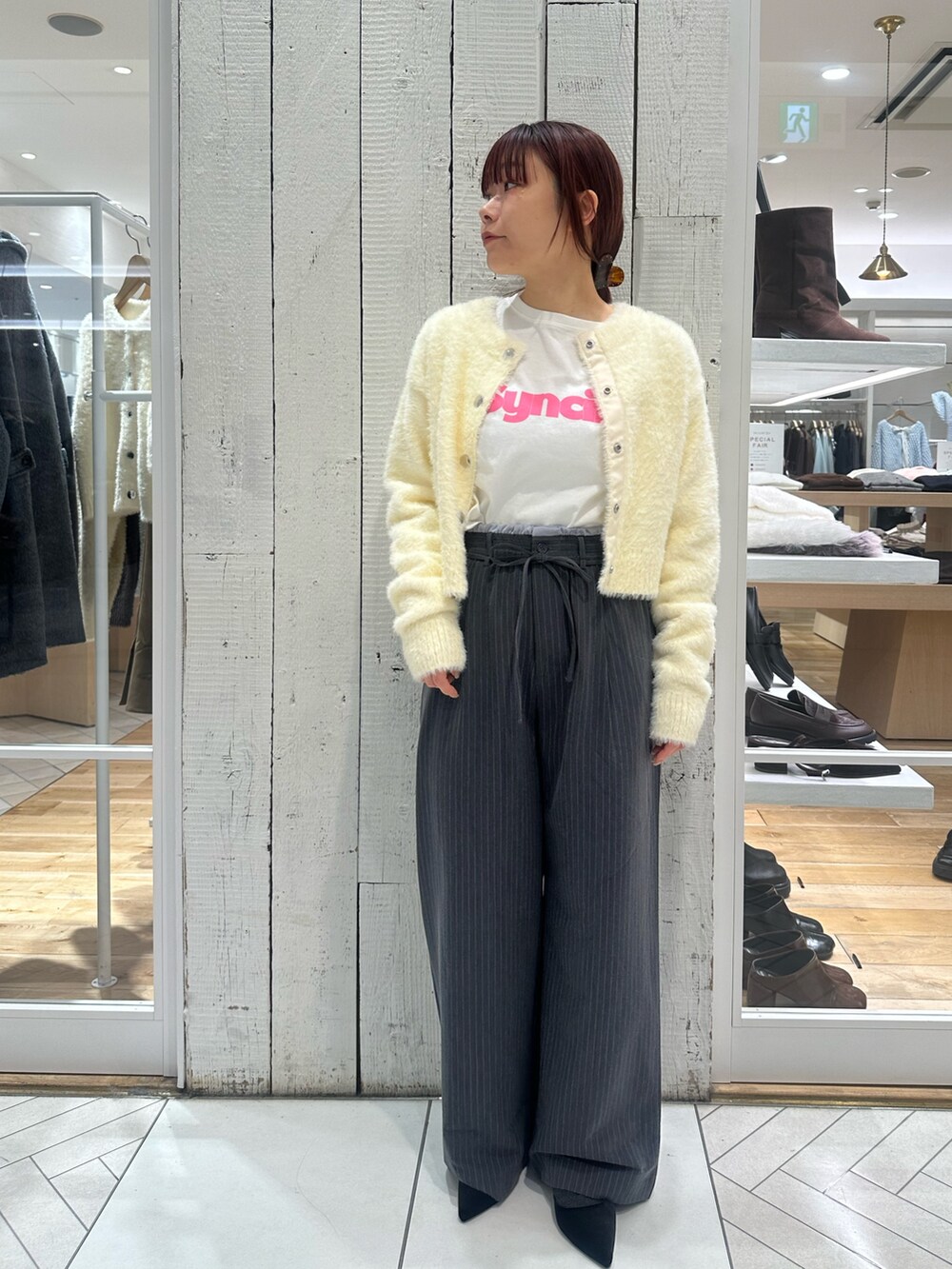 グレー系のスラックス、ホワイト系のカーディガン/ボレロ、ホワイト系のTシャツ/カットソーを着用したレディースの冬コーディネートの2枚目の写真