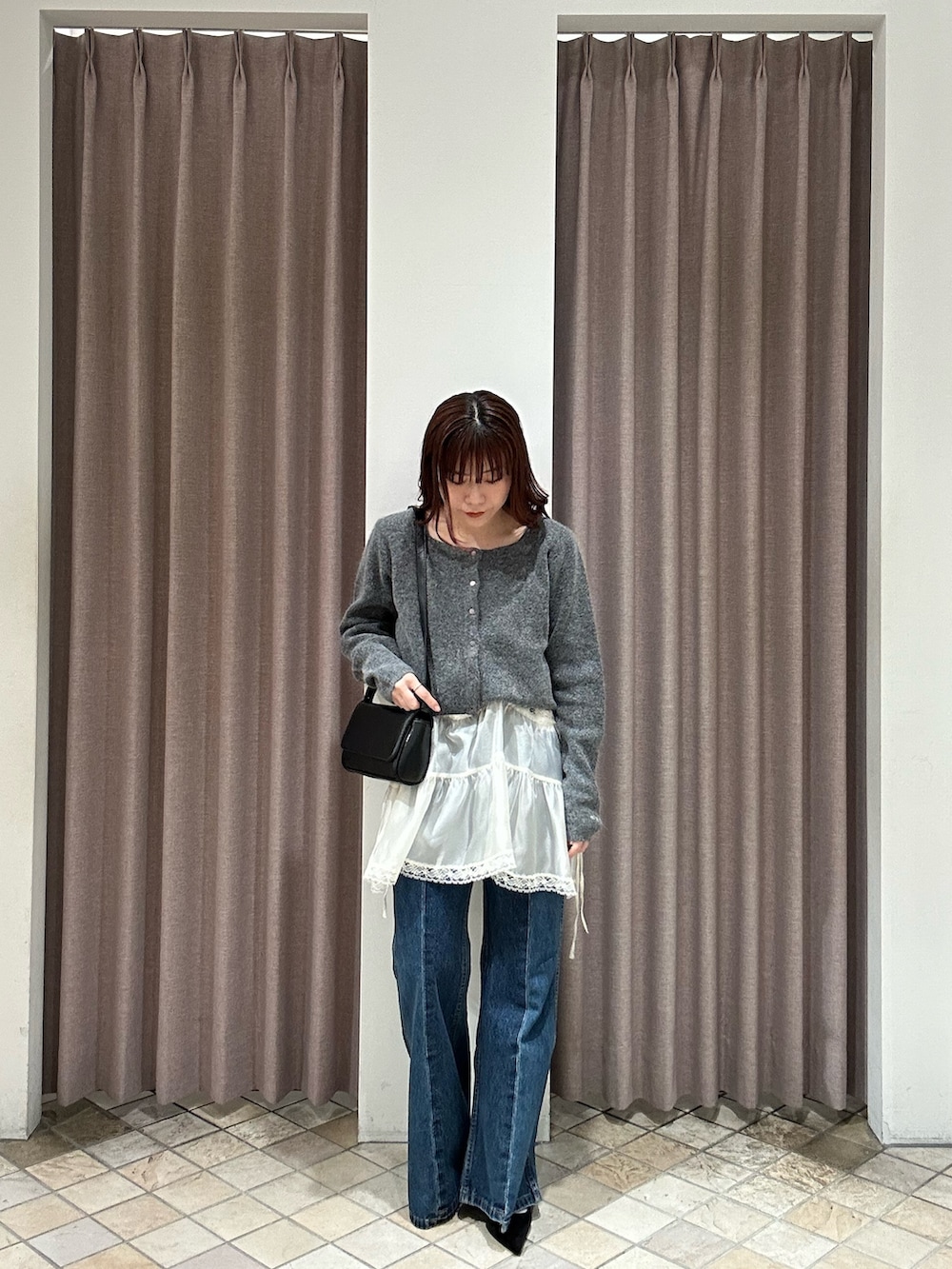 ブラック系のその他アウター、ブラック系のトートバッグ、ブルー系のデニムパンツを着用したレディースの秋コーディネートの4枚目の写真