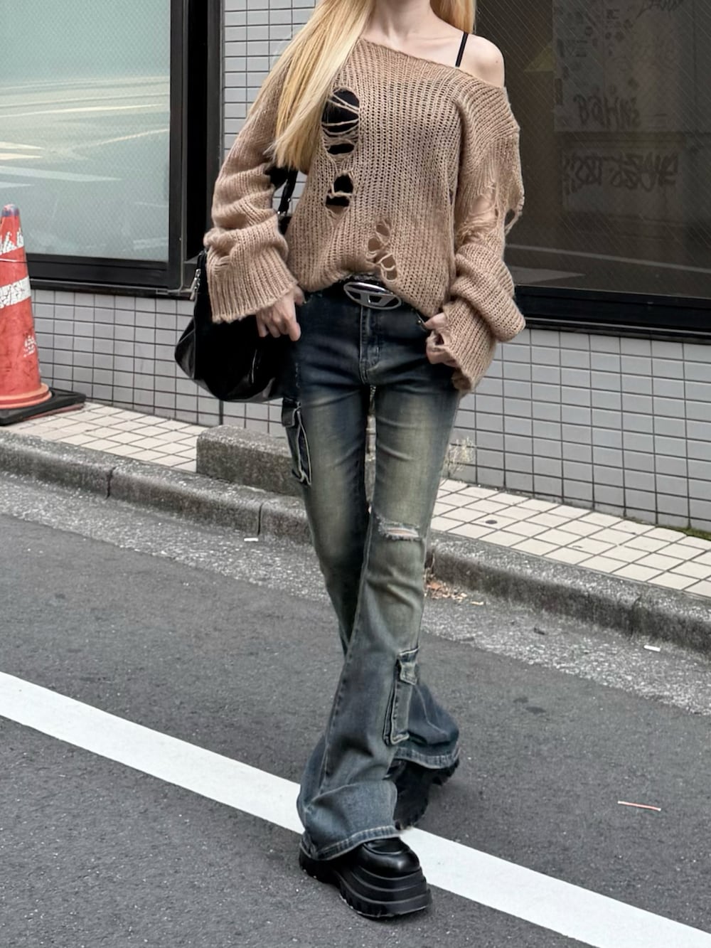 ブルー系のデニムパンツ、ブラック系のボストンバッグ、ベージュ系のニット/セーターを着用したレディースの秋コーディネートの2枚目の写真