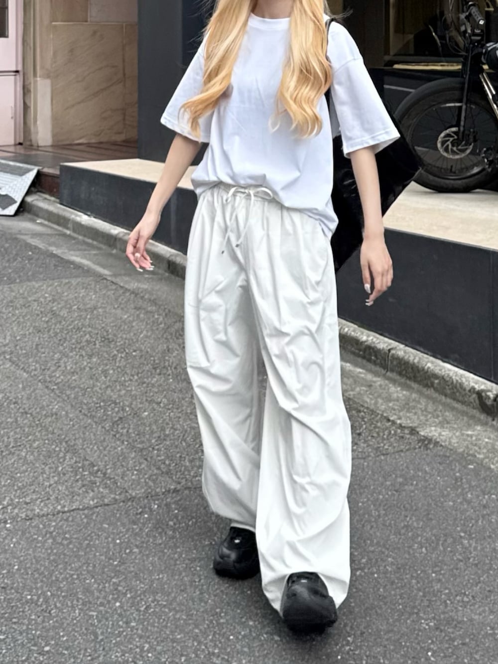 ブラック系のスニーカー、ホワイト系のTシャツ/カットソー、ホワイト系のパンツを着用したレディースの夏コーディネートの2枚目の写真