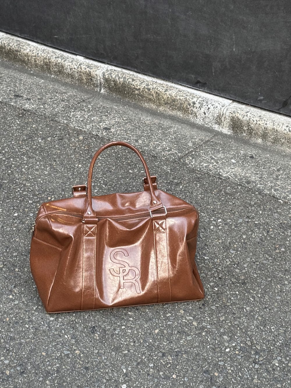 ブラック系のデニムパンツ、ブラック系のTシャツ/カットソー、ブラウン系のボストンバッグを着用したレディースの秋コーディネートの4枚目の写真