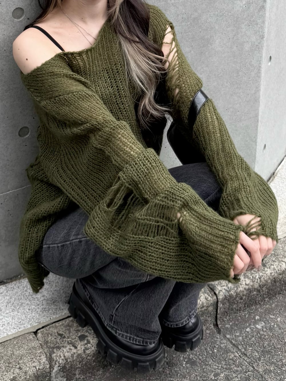 グリーン系のニット/セーター、ブラック系のショルダーバッグ、ブラック系のデニムパンツを着用したレディースの秋コーディネートの3枚目の写真