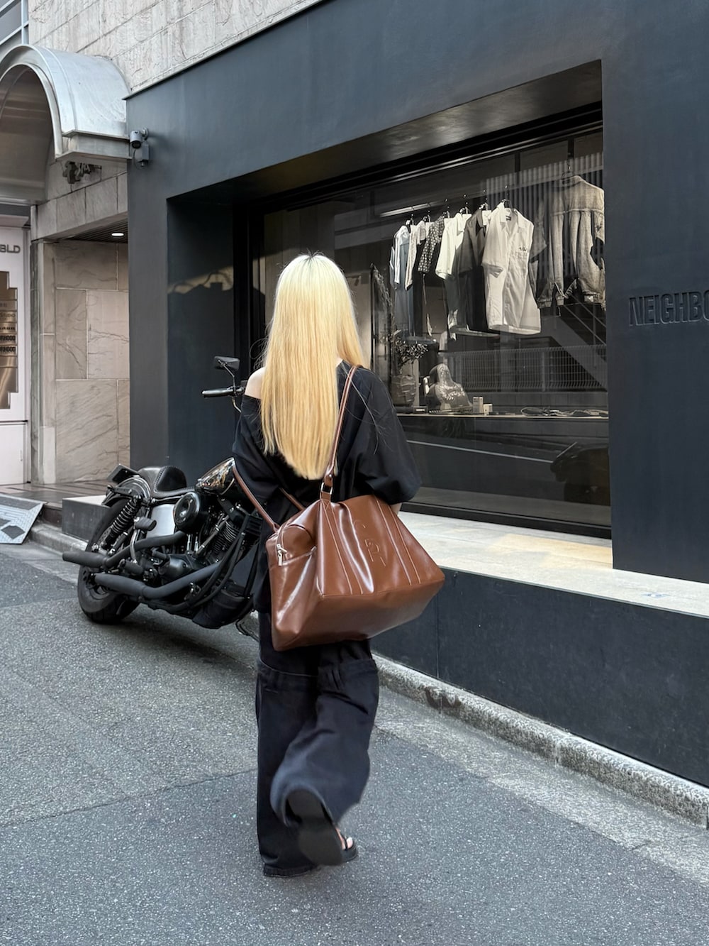 ブラック系のデニムパンツ、ブラック系のTシャツ/カットソー、ブラウン系のボストンバッグを着用したレディースの秋コーディネートの2枚目の写真