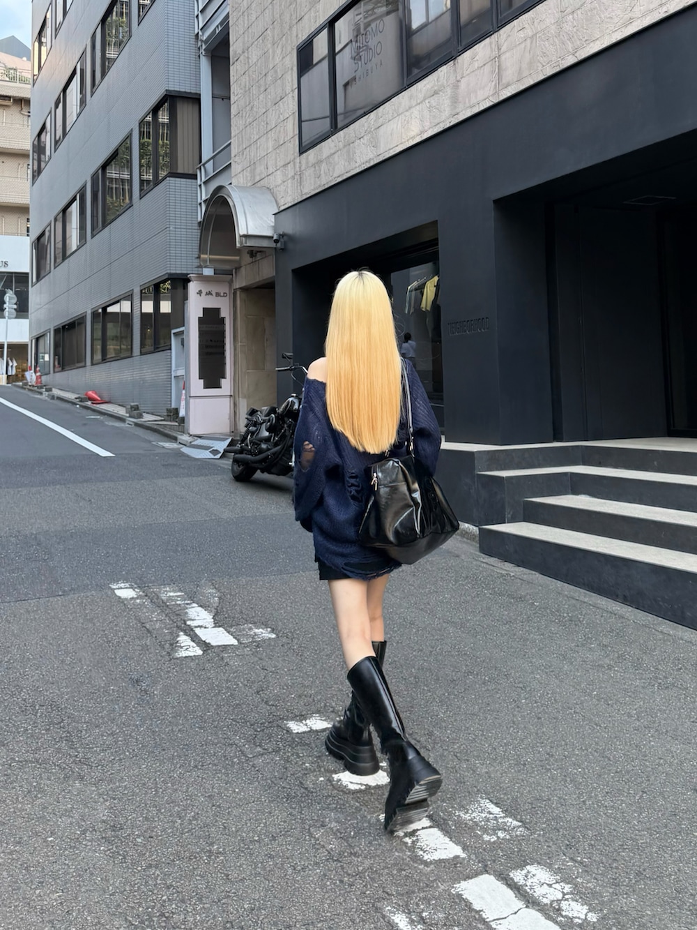 ブラック系のブーツ、ブルー系のニット/セーター、ブラック系のスカートを着用したレディースの秋コーディネートの2枚目の写真