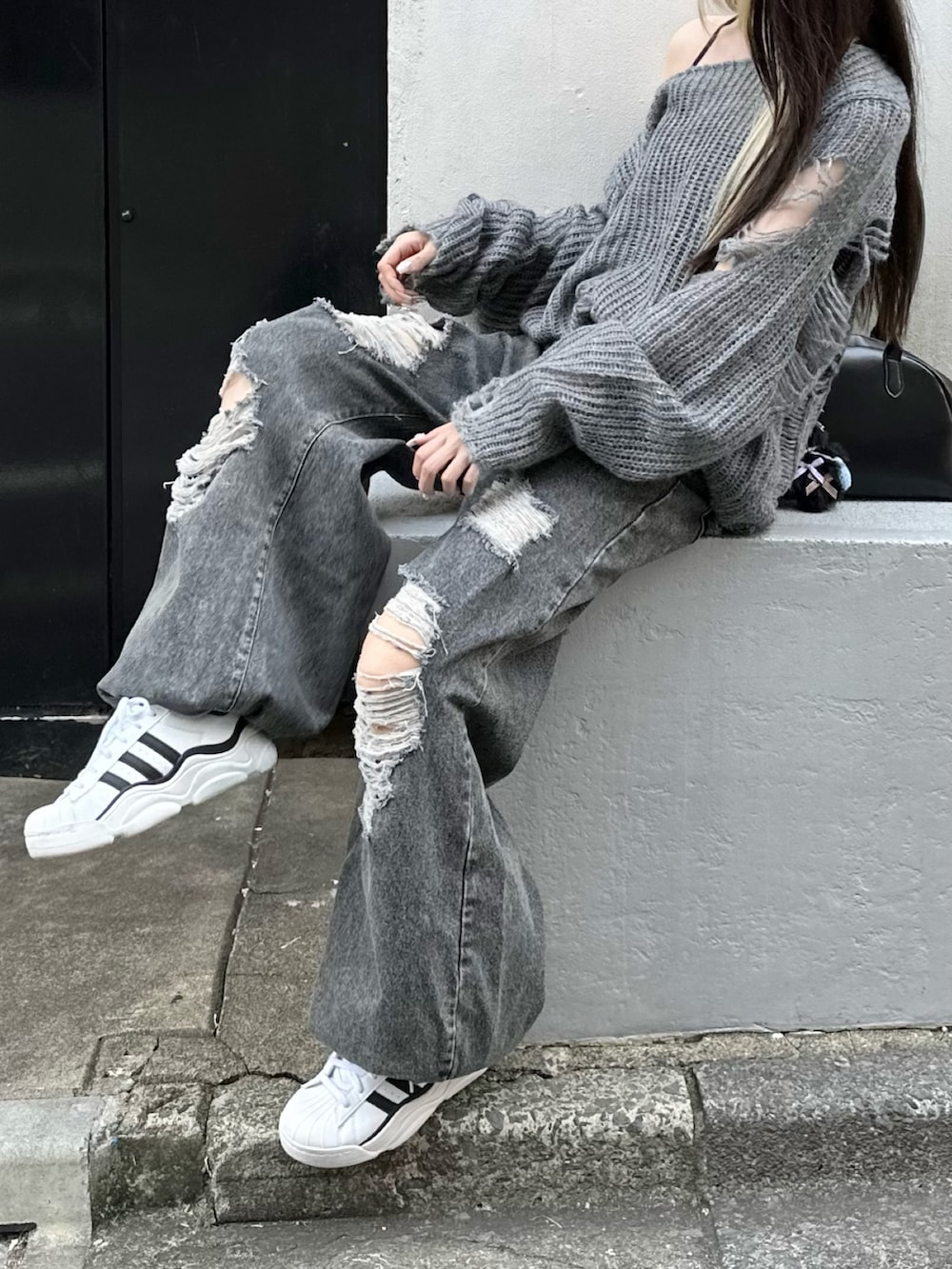ブラック系のデニムパンツ、ホワイト系のスニーカー、グレー系のニット/セーターを着用したレディースの秋コーディネートの3枚目の写真