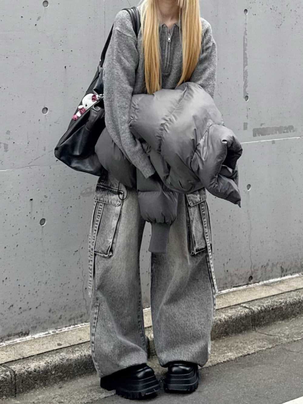 グレー系のダウンジャケット/コート、グレー系のデニムパンツ、ブラック系のボストンバッグを着用したレディースの冬コーディネートの2枚目の写真